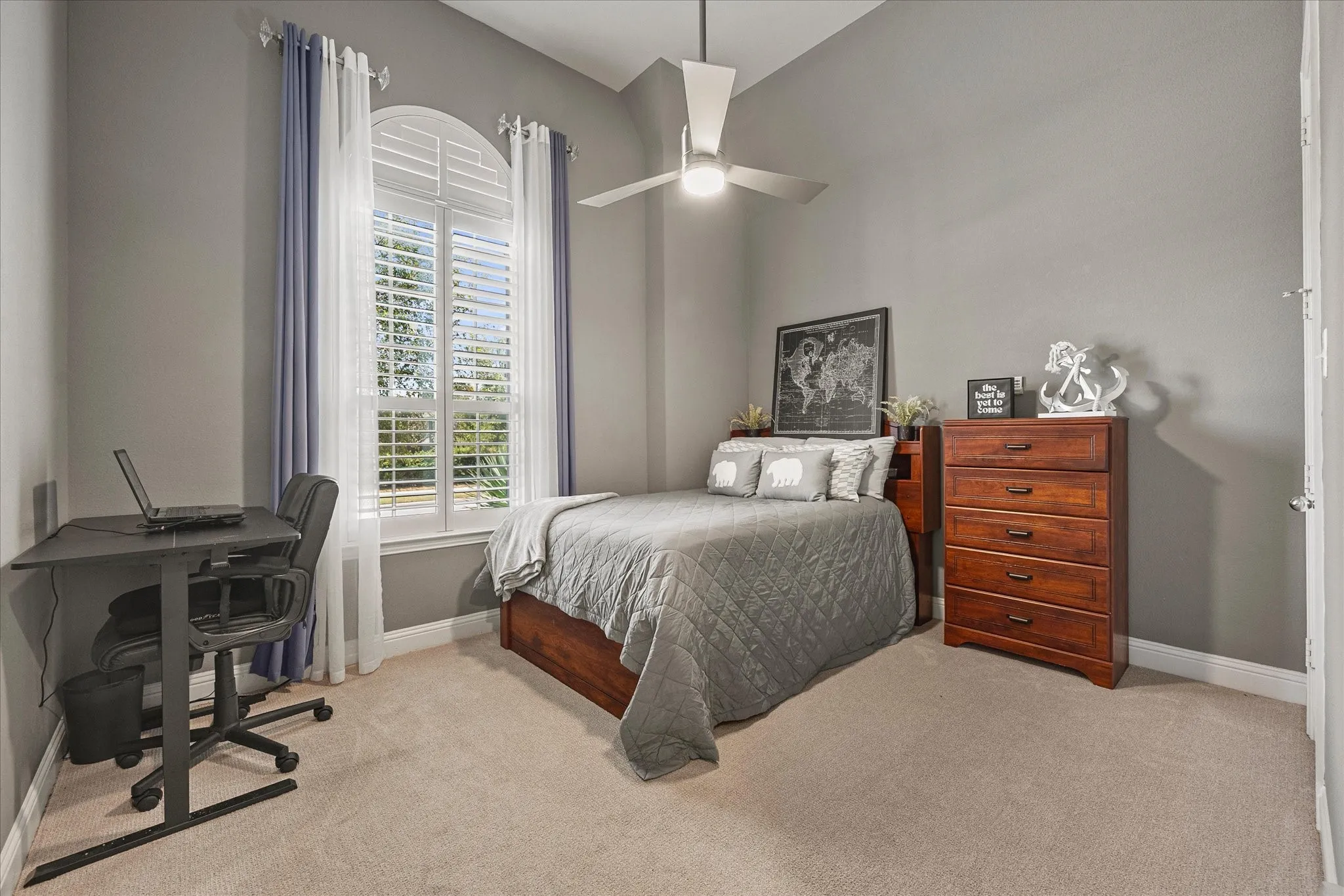 Arched window with plantation shutters, light neutral carpeting, and a ceiling fan with integrated lighting
