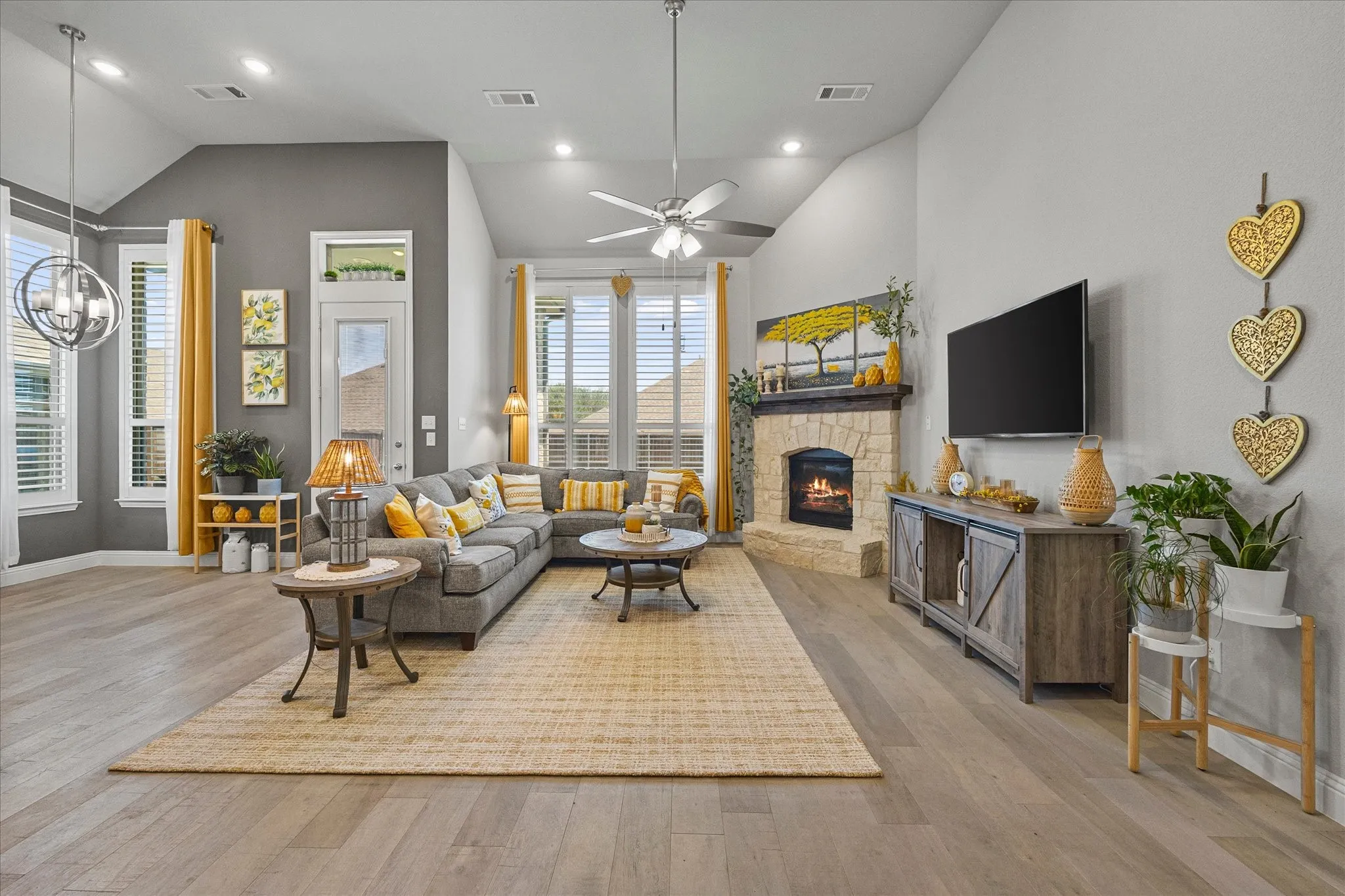High vaulted ceilings, wood-finish flooring, recessed lighting, ceiling fan, and a stone-clad fireplace