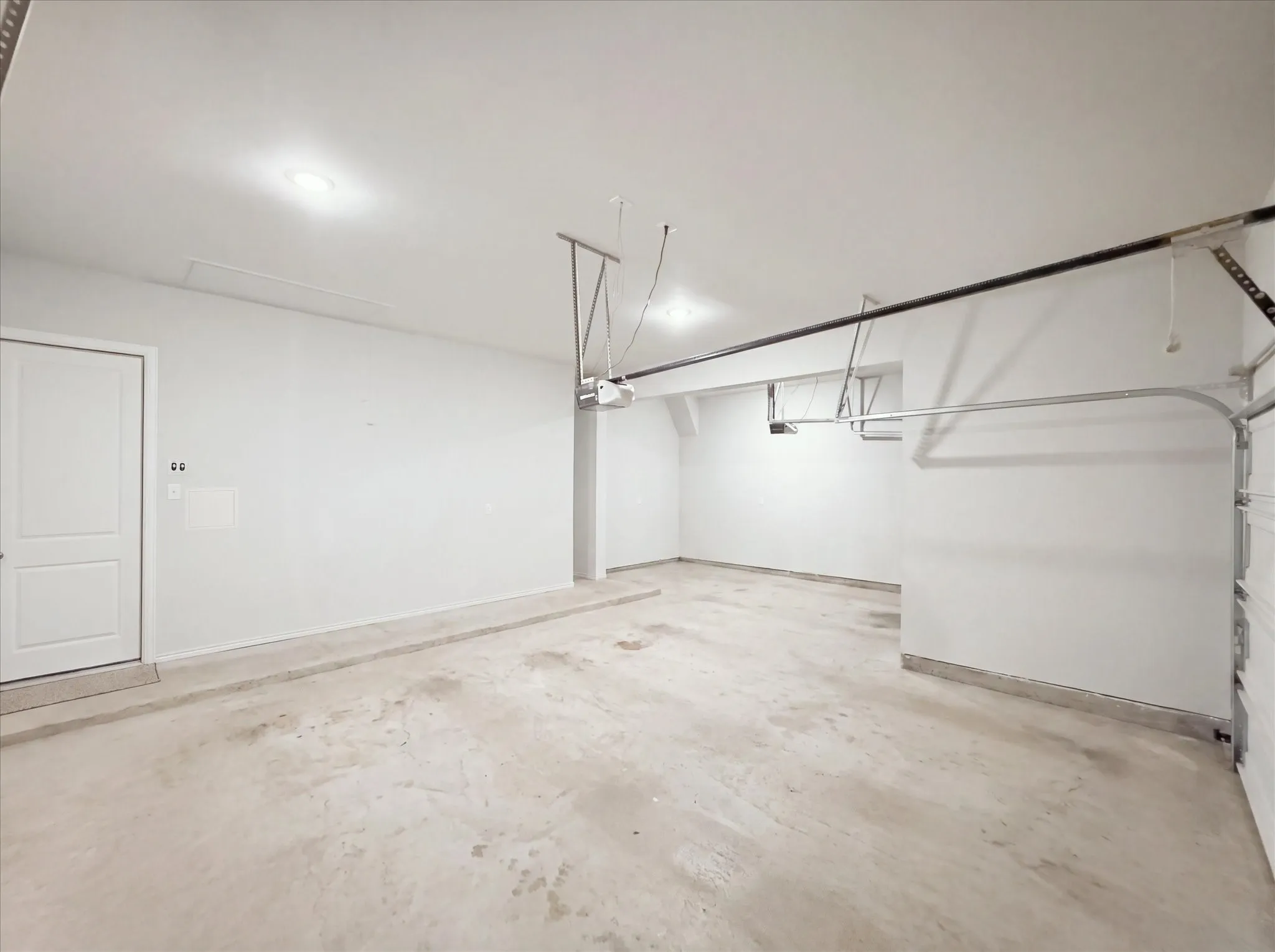 Attached garage featuring a concrete floor, white walls, and a paneled door