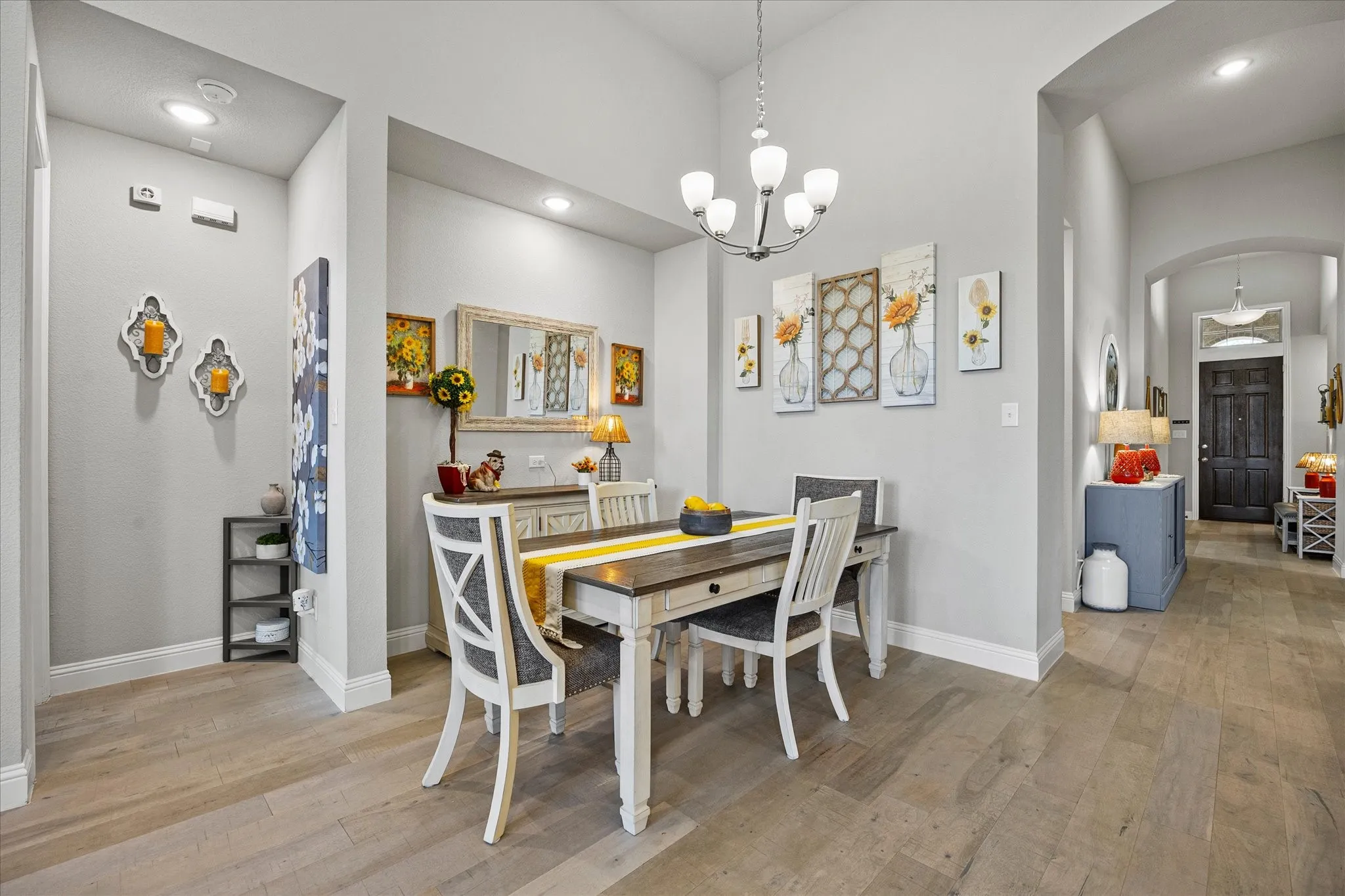 Vaulted ceiling with a chandelier, light wood-finish flooring, recessed lighting, and arched doorways