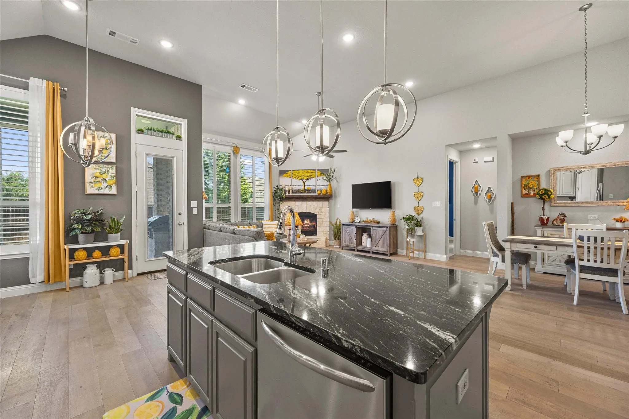 Spacious open-concept living area featuring a kitchen island with integrated sink, vaulted ceilings, and recessed lighting