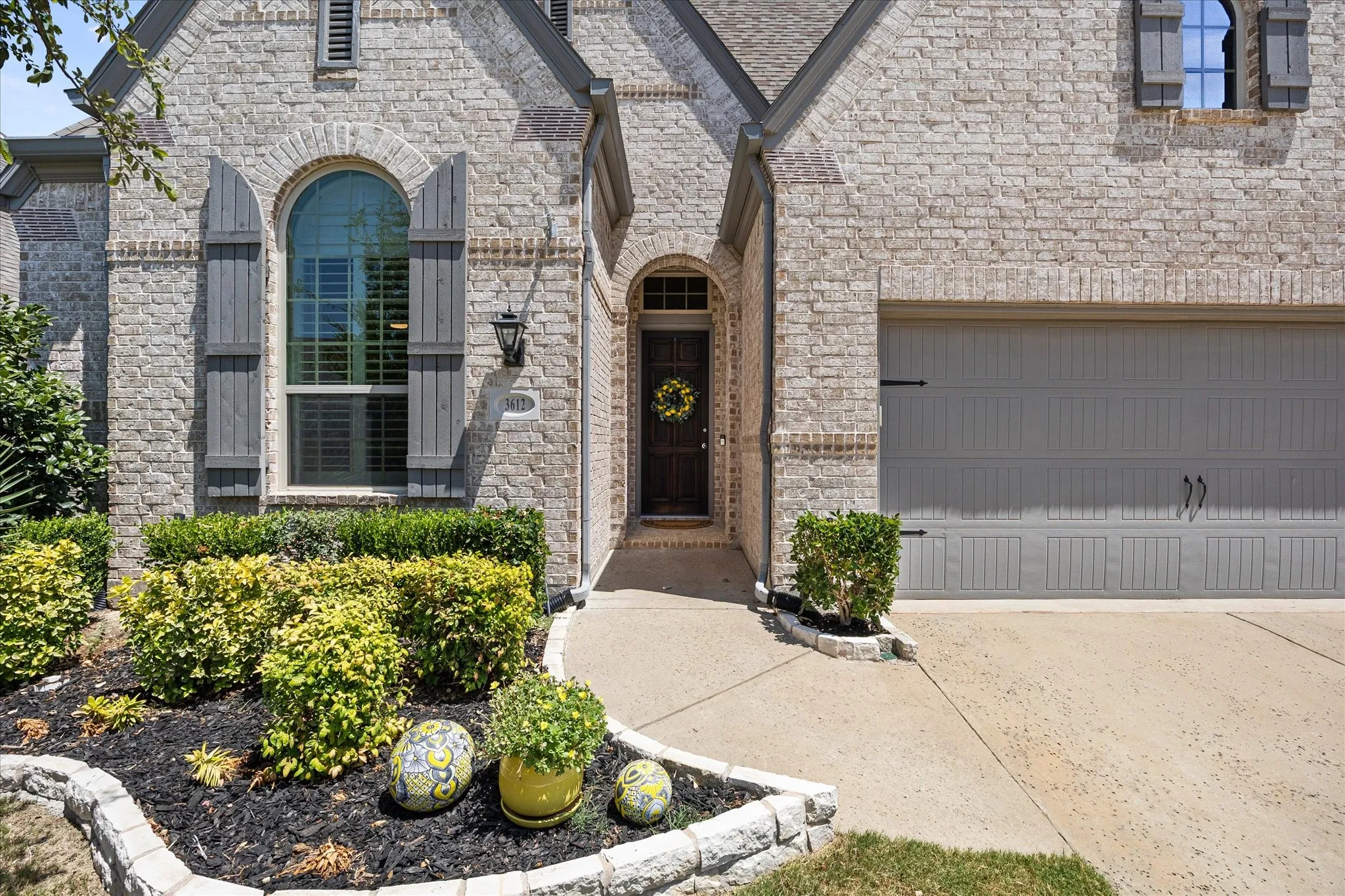 Light-colored brick exterior with gray shutters and a matching garage door