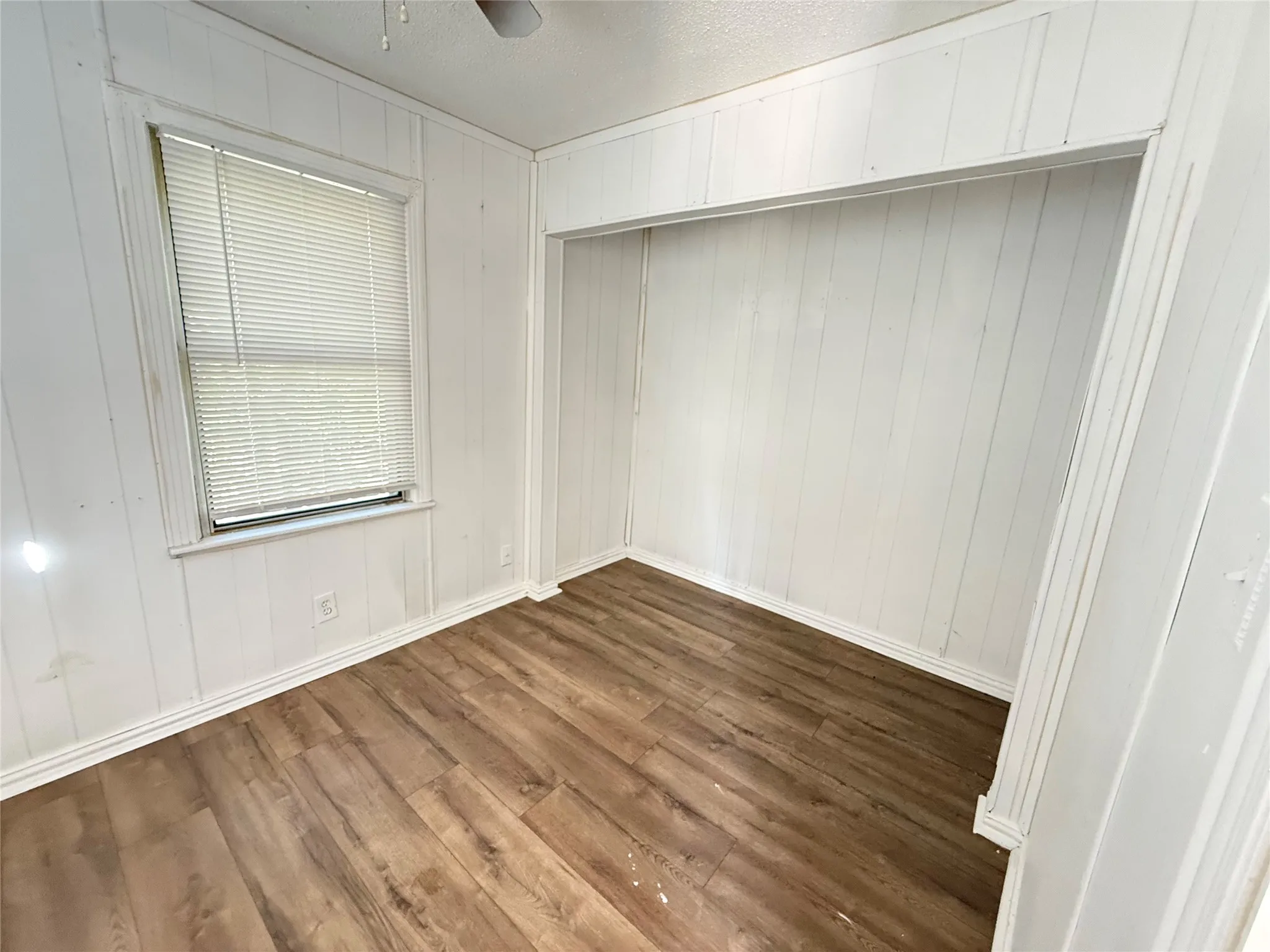 Wood-finish flooring, white paneled walls, and a recessed alcove