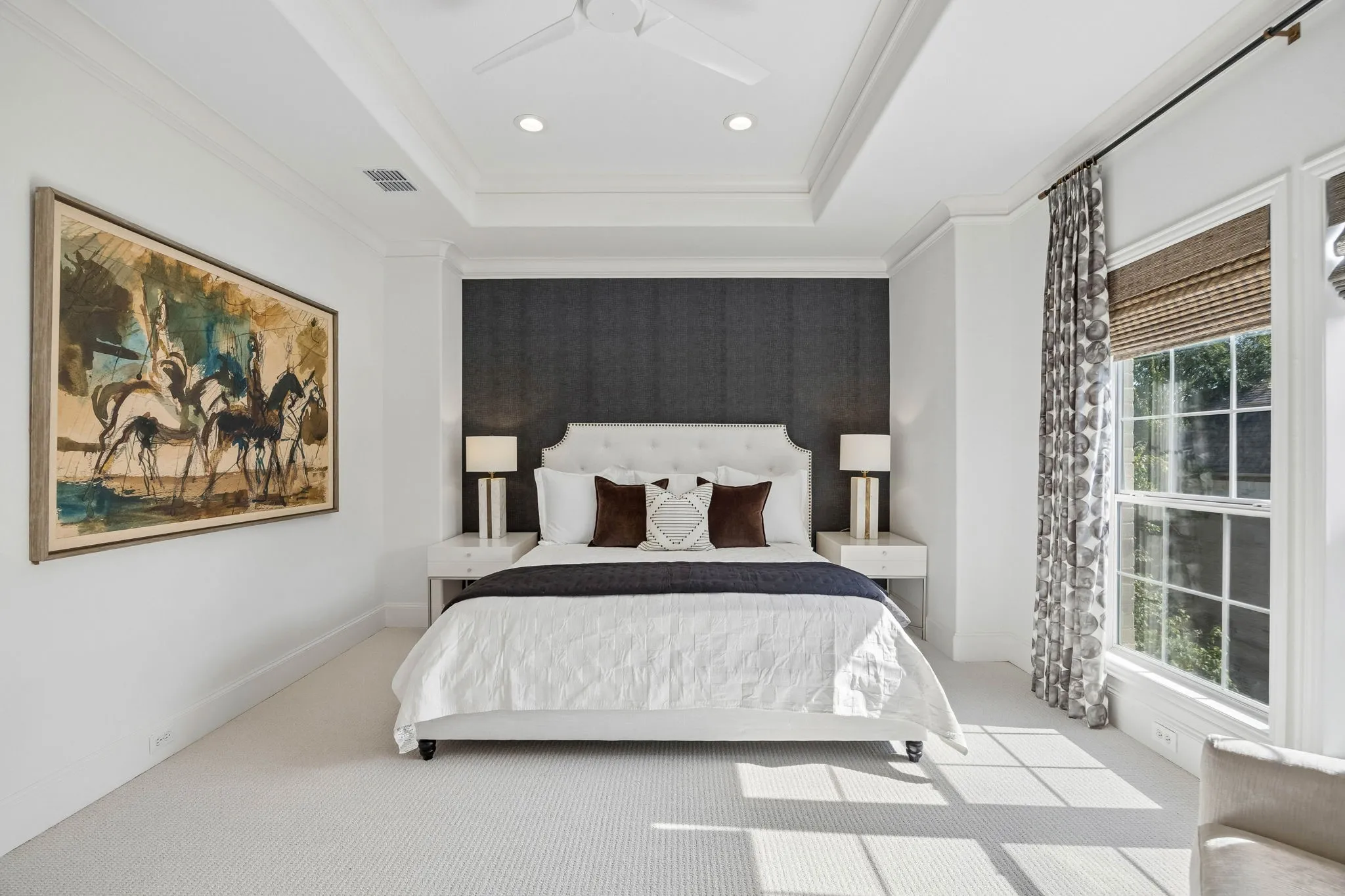 Primary suite with a custom walk-in closet system. Designer wallpapered accent wall, woven shades and custom blackout drapery.