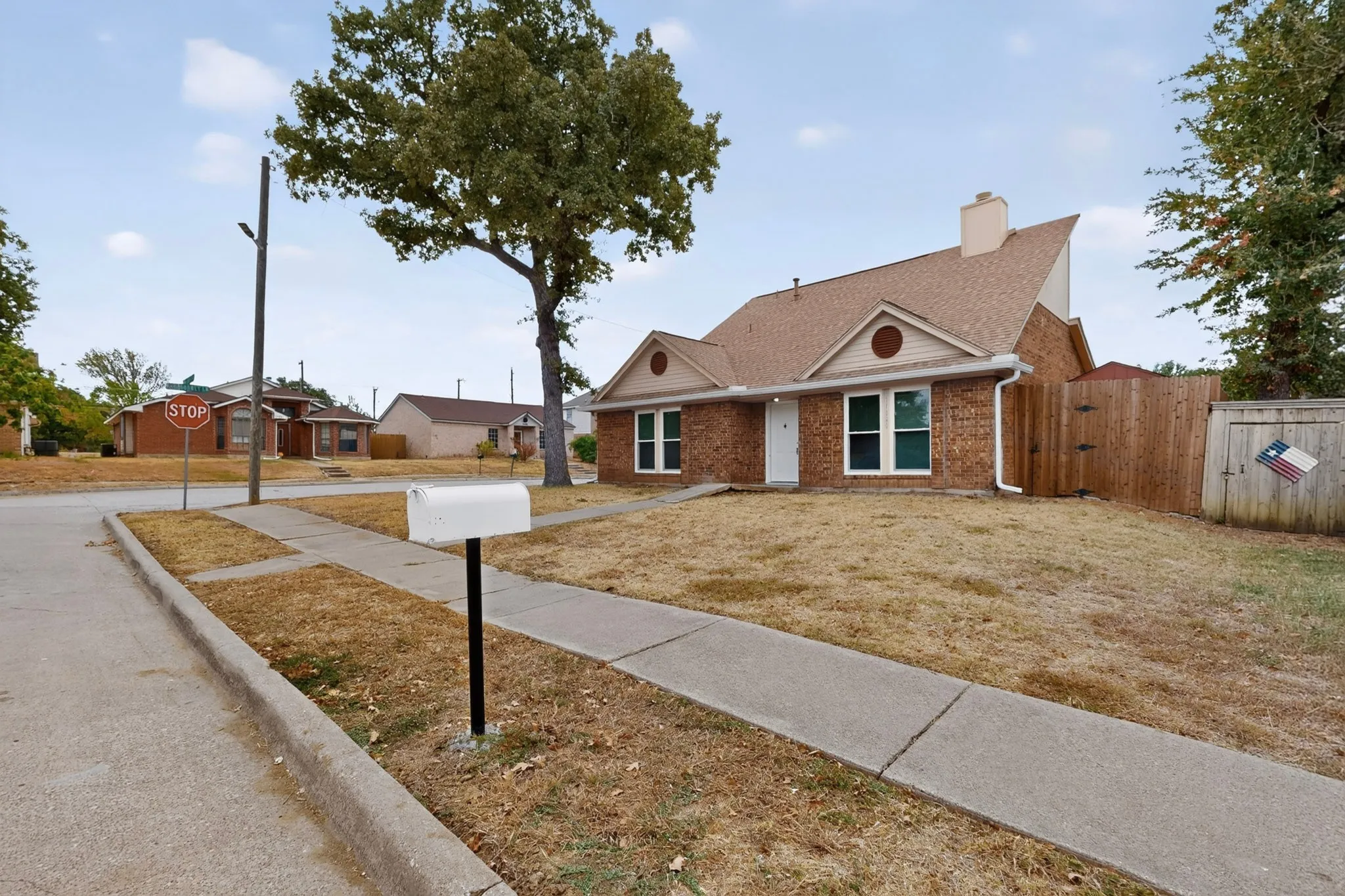 Brick exterior with gabled roofline, multiple windows, and a privacy fence