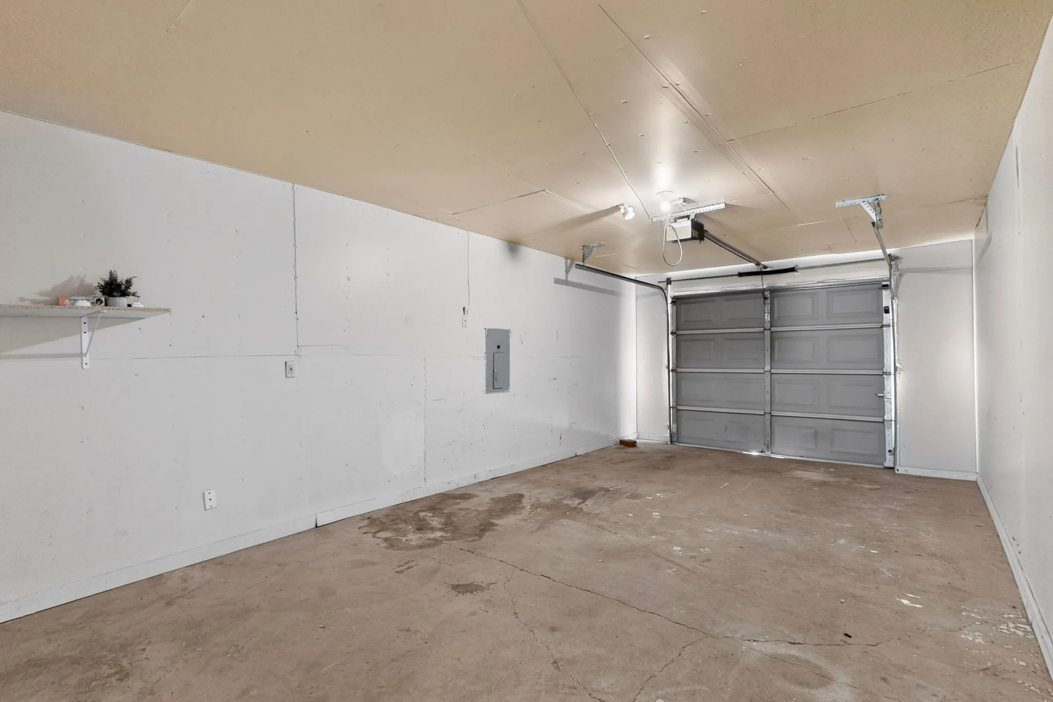 Finished interior garage with an automatic garage door opener and a mounted electrical panel