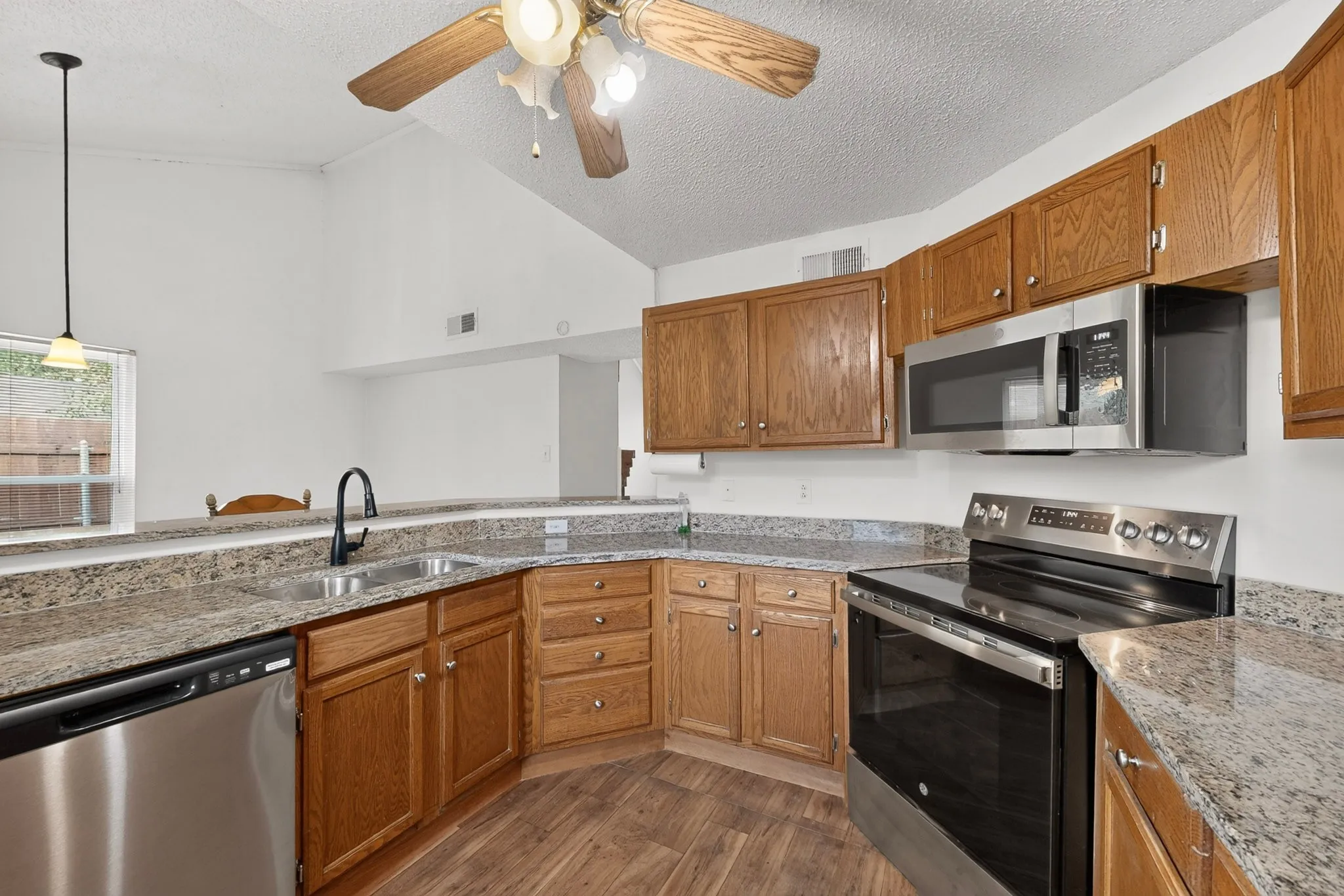 Kitchen featuring wood-finish flooring, stainless steel appliances, and a double basin sink with a matte black faucet