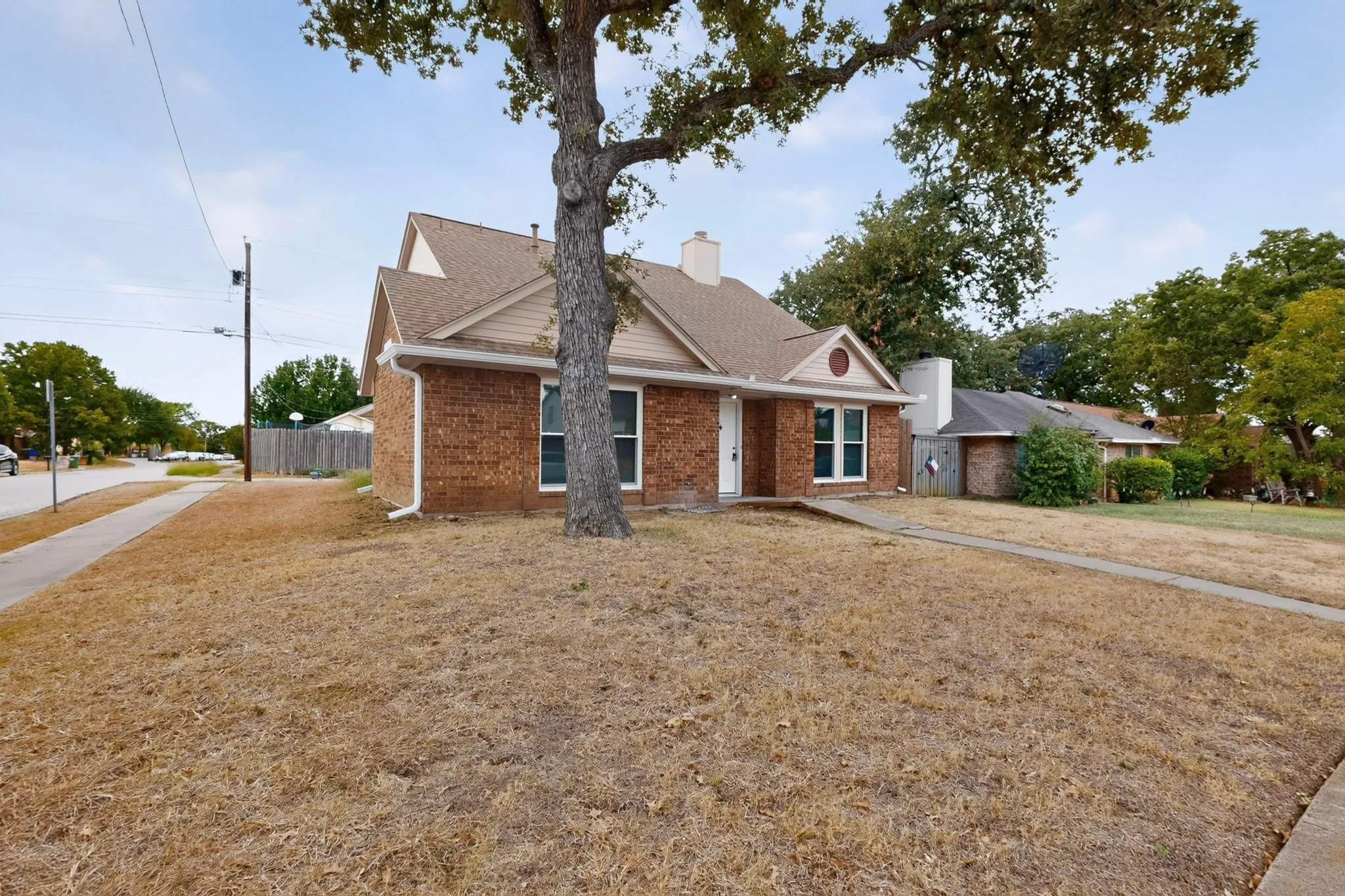 Brick exterior with a peaked roofline, a prominent chimney, and a concrete sidewalk leading to the front entry