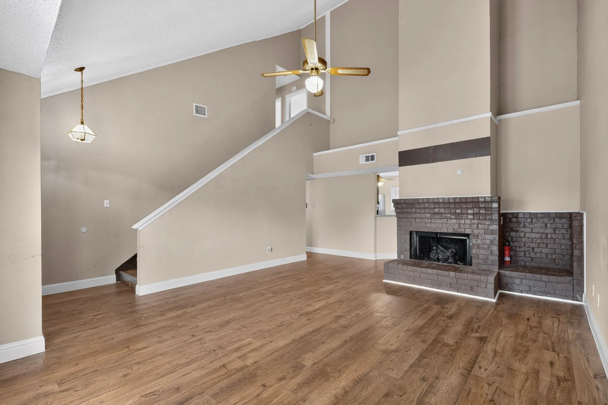 Vaulted ceilings, wood-finish flooring, and a brick-surround fireplace with a hearth