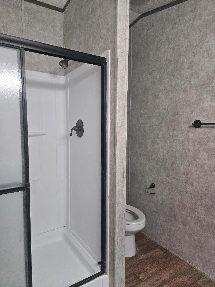 Shower enclosure with dark frame, white shower surround, and a brushed nickel shower head