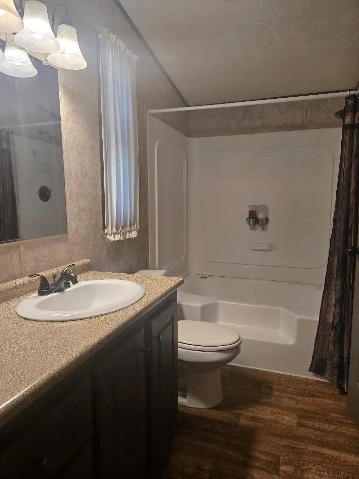 Bathroom featuring a single vanity with dark wood-finish cabinetry, a white oval sink, and a speckled countertop