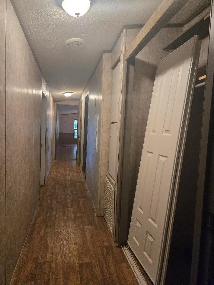 Hallway featuring wood-finish flooring, flush mount lighting, and panel-style walls
