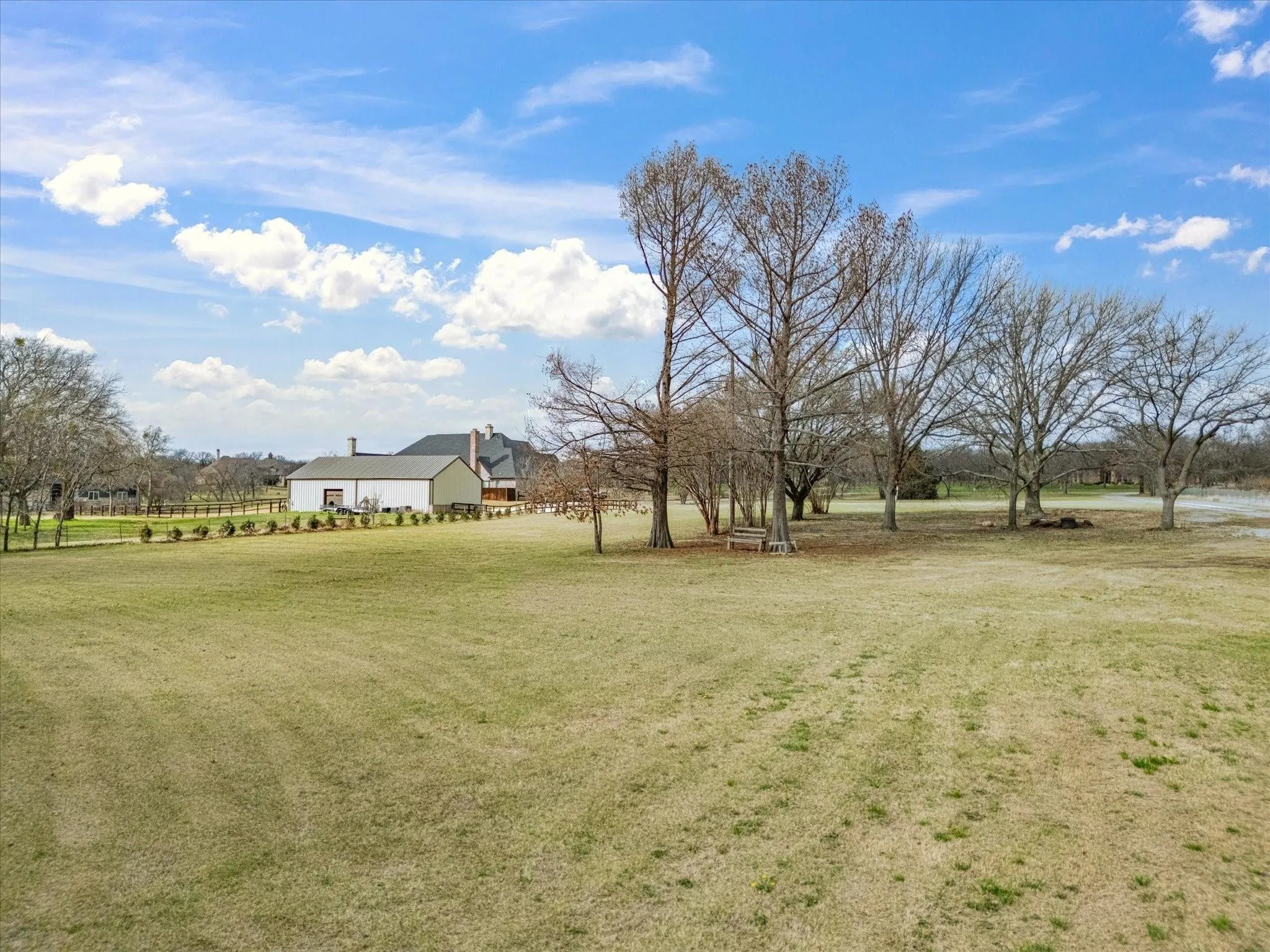 Expansive grassy grounds with mature trees and a white-sided outbuilding