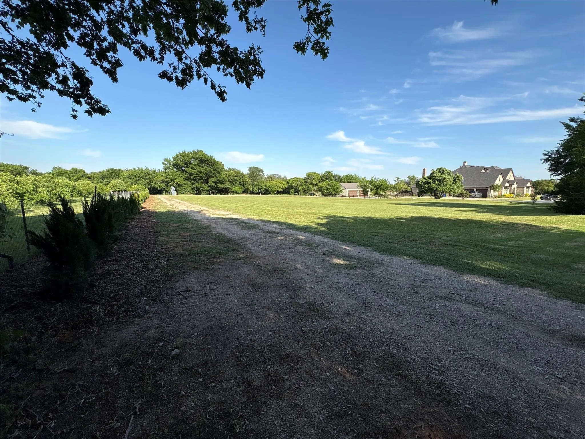 Expansive grassy lawn with a gravel path and mature trees
