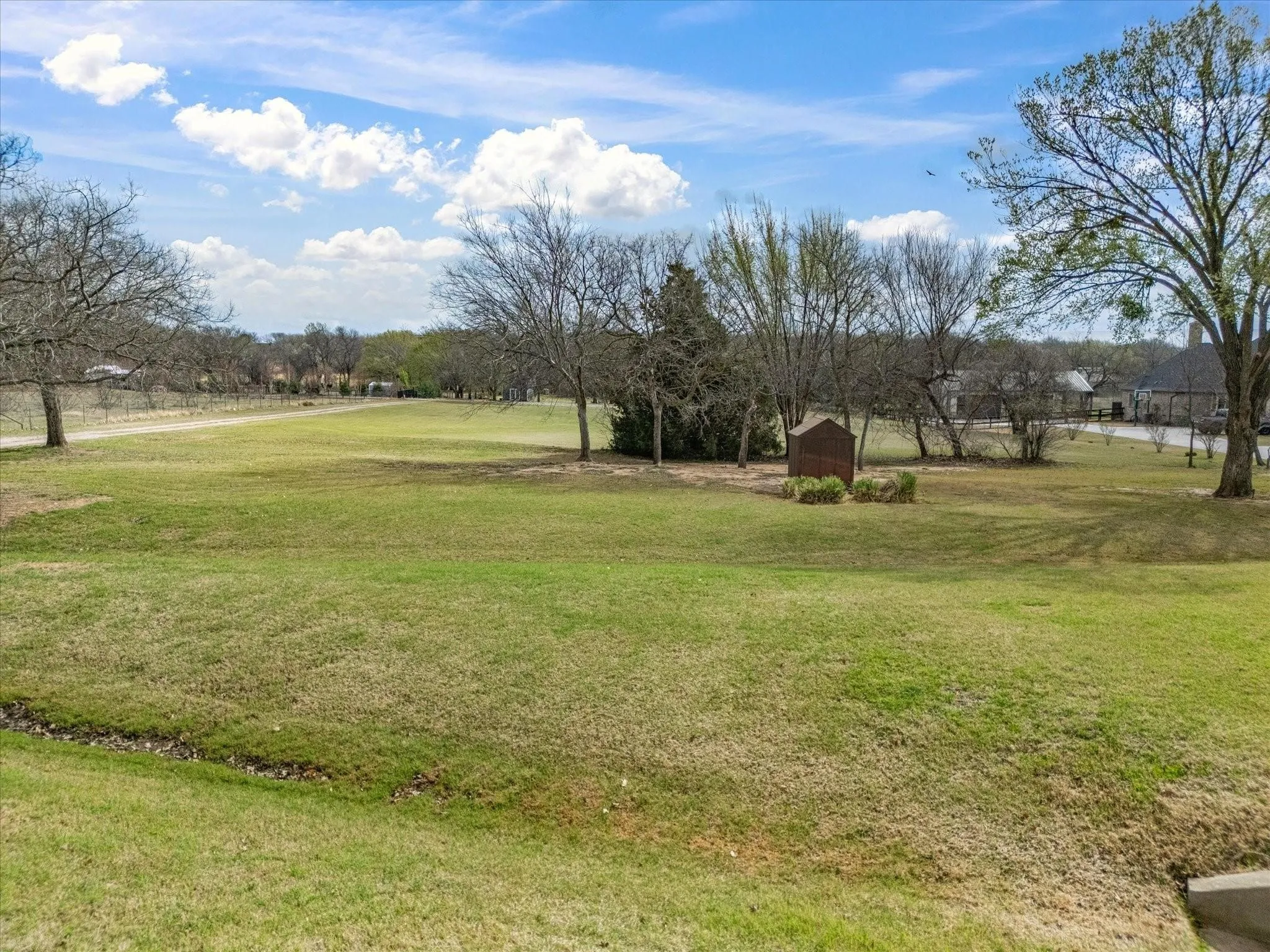 Expansive green space featuring mature trees and a clear sky