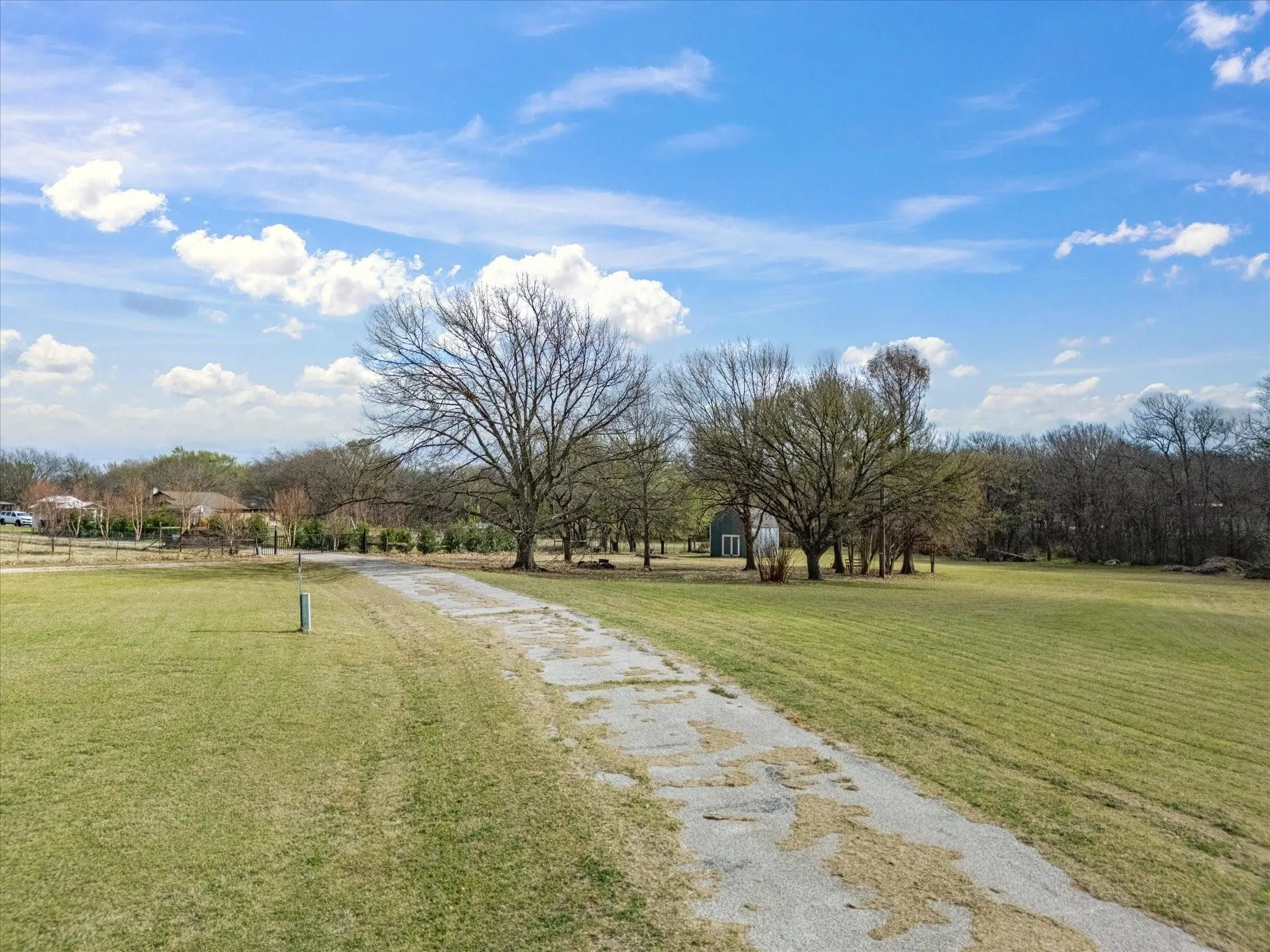 Expansive green space featuring a long driveway and mature trees