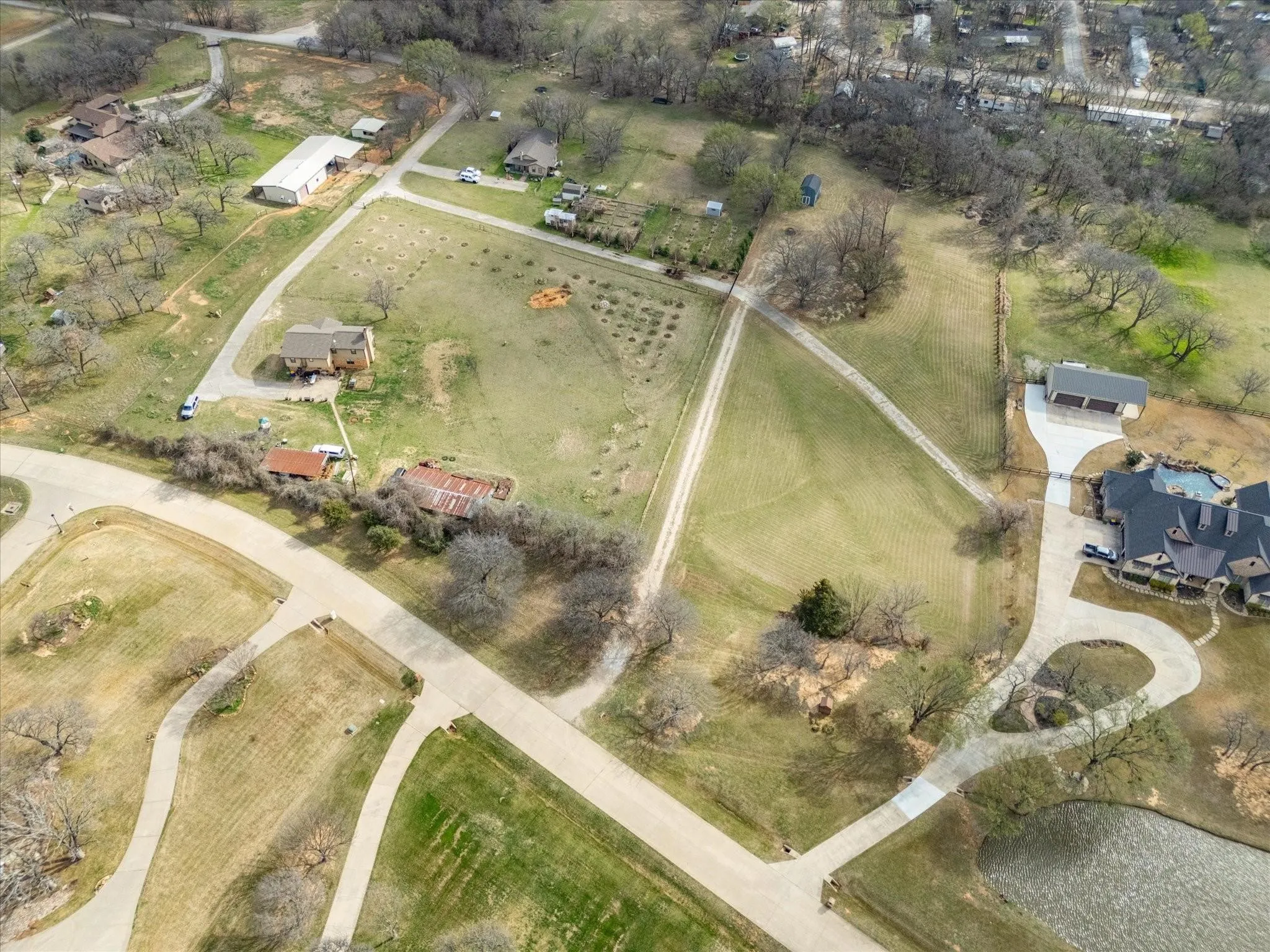 Expansive property featuring multiple structures, paved driveways, a pond, and abundant open land