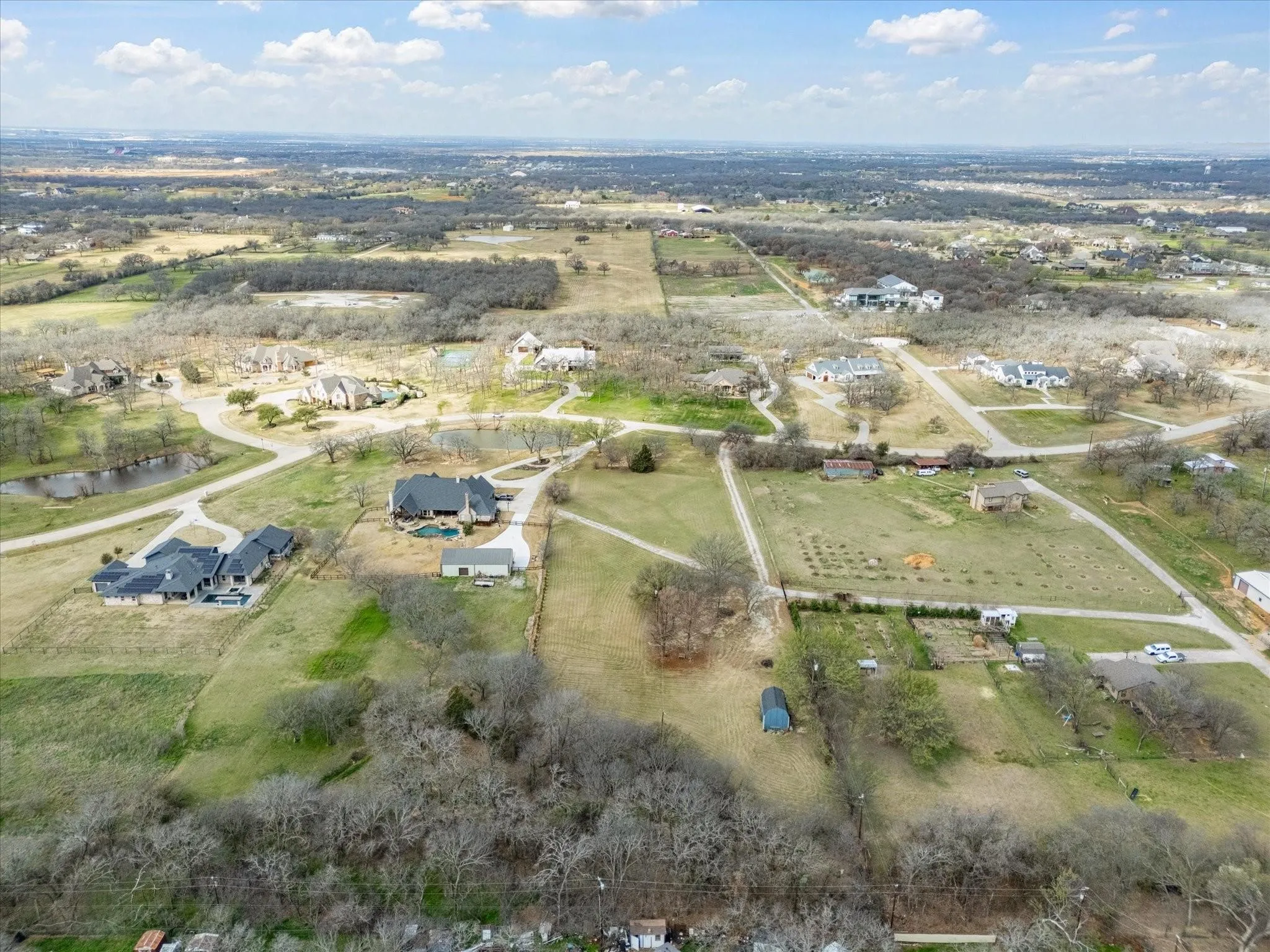 Aerial overview revealing multiple residential properties, expansive land plots, and scattered natural areas