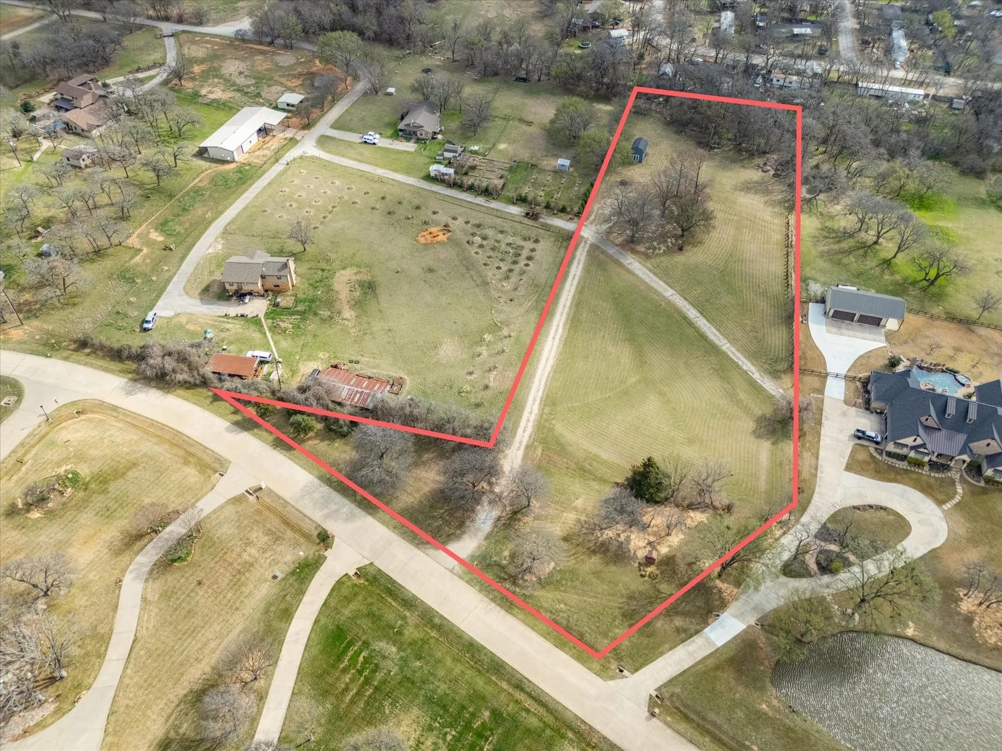 Expansive land parcel with a visible structure, a winding dirt path, and a distinct boundary marked by a red outline