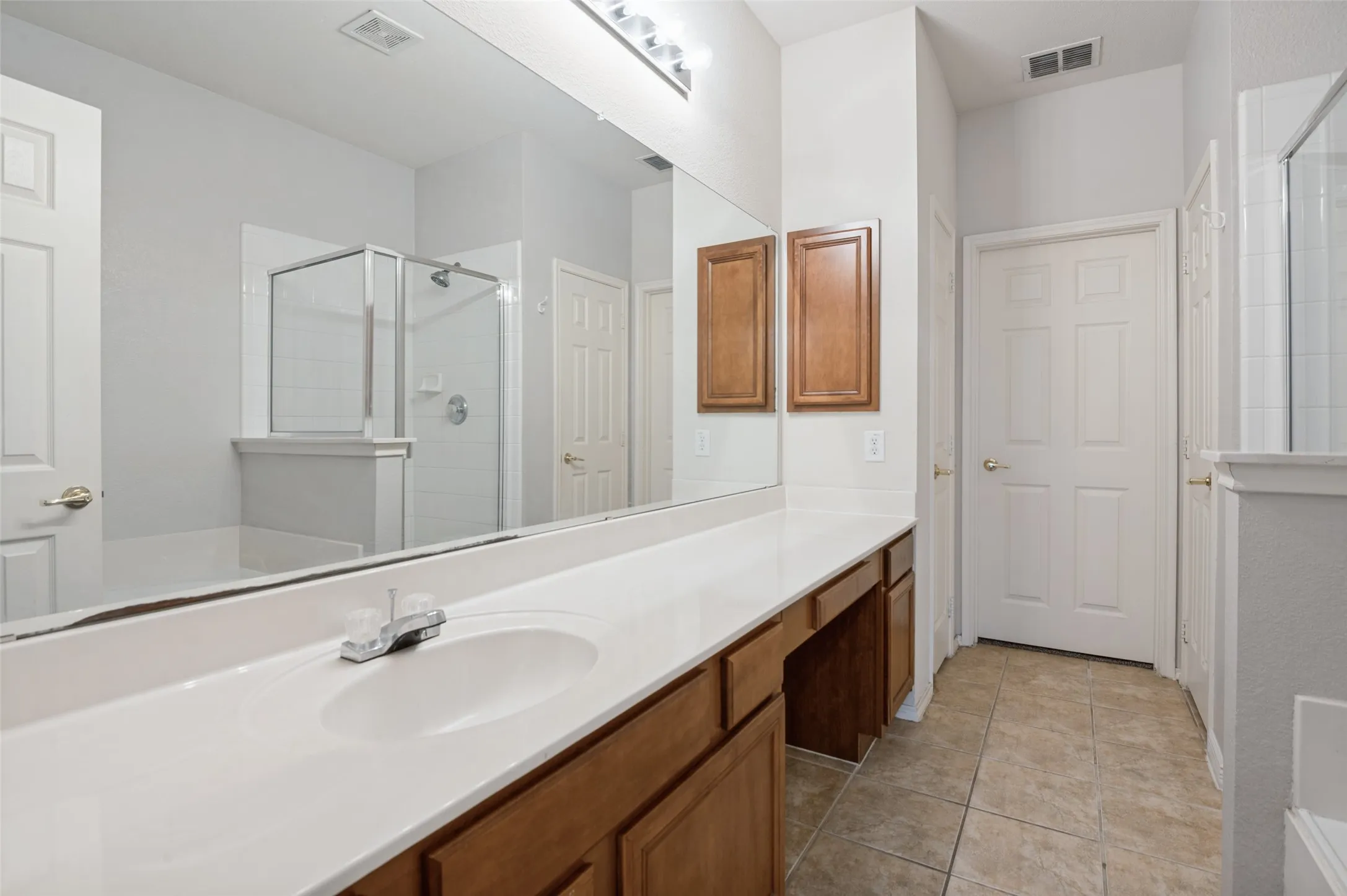 Extended vanity with integrated sink, wood-finish cabinetry, and a full-width mirror