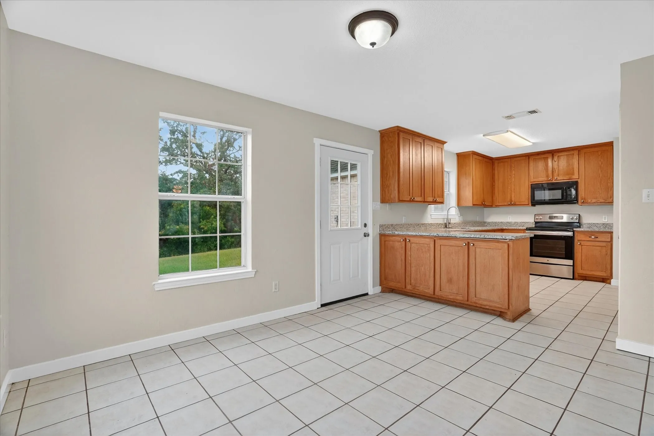 Kitchen featuring wood cabinetry, light-toned countertops, and stainless steel appliances