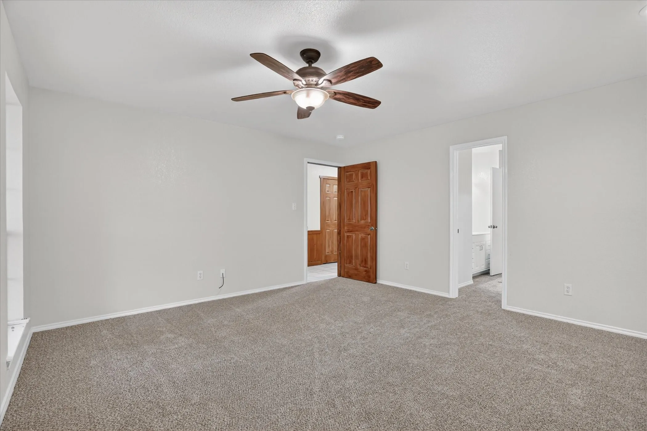 Expansive carpeting, neutral wall finishes, wood-finish doors, and a ceiling fan with integrated lighting