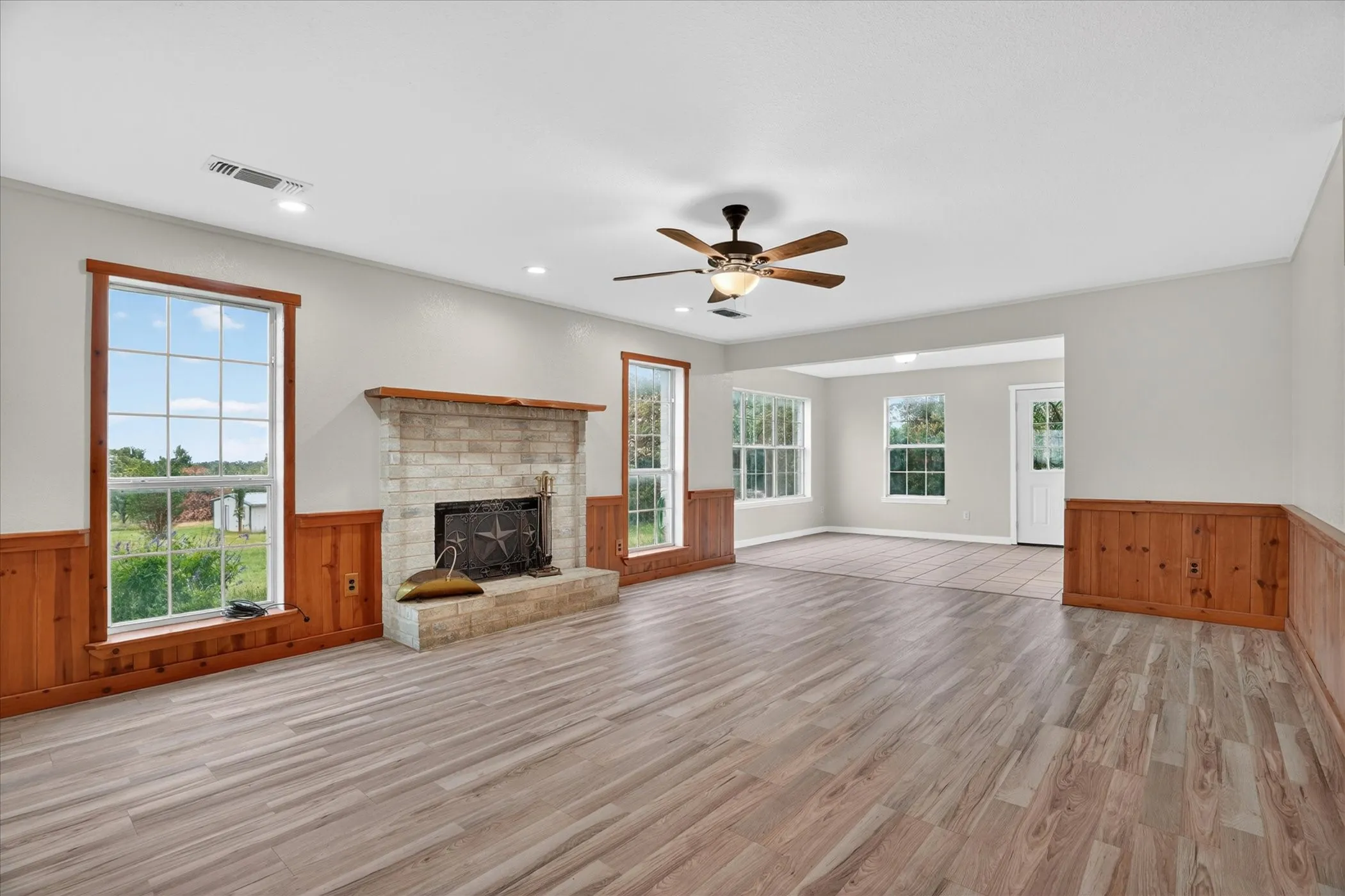 Wood-finish flooring throughout, featuring a stone-clad fireplace with hearth, recessed lighting, and a ceiling fan