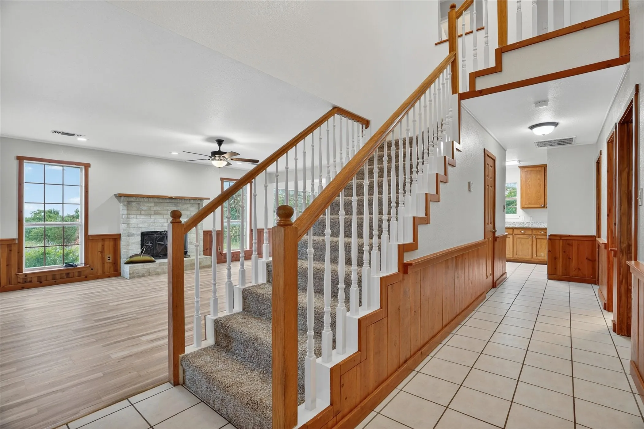 Carpeted staircase with wood railing, white balusters, and wood paneling