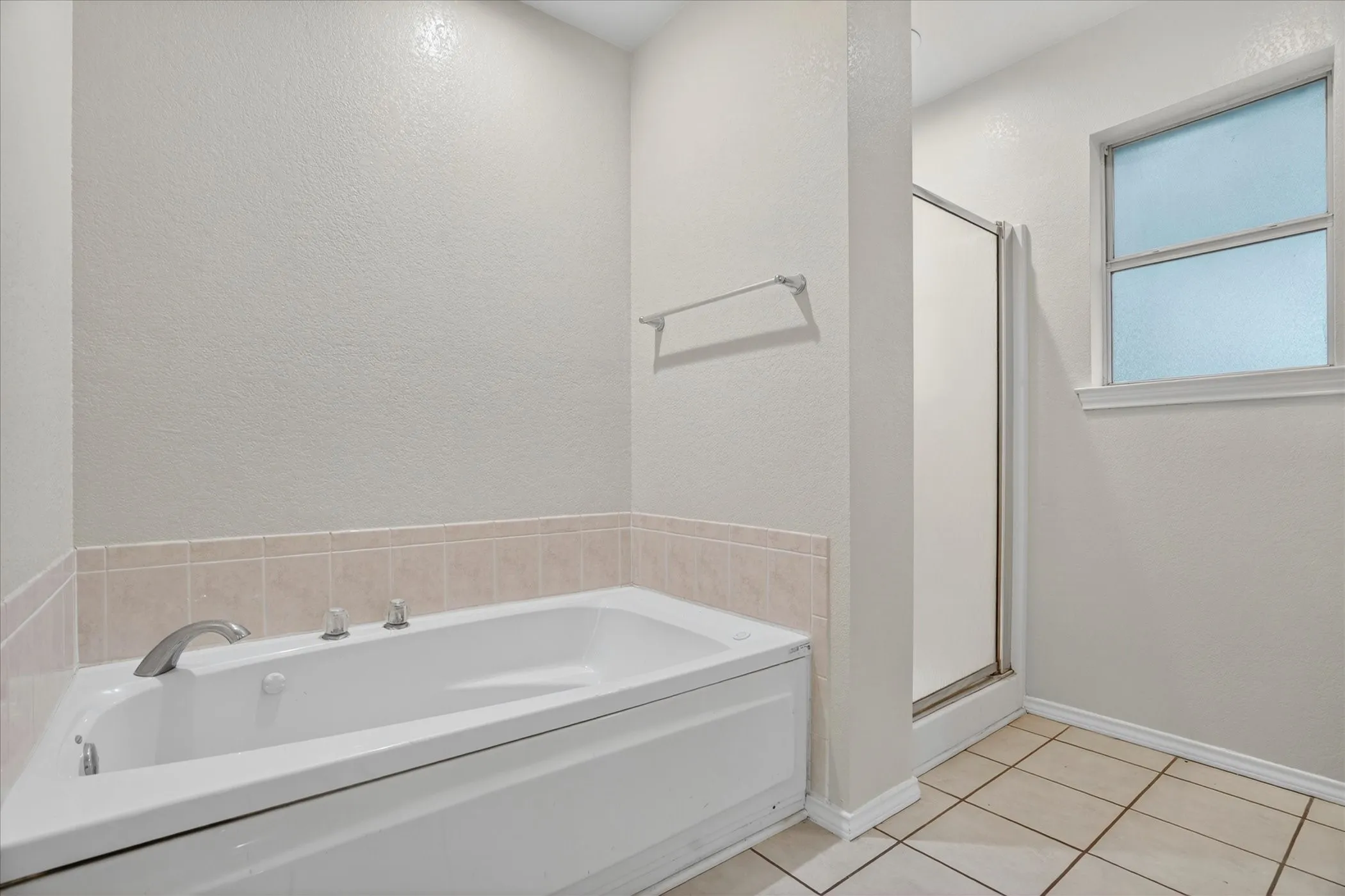 Soaking tub with tile surround, enclosed shower, and tile flooring