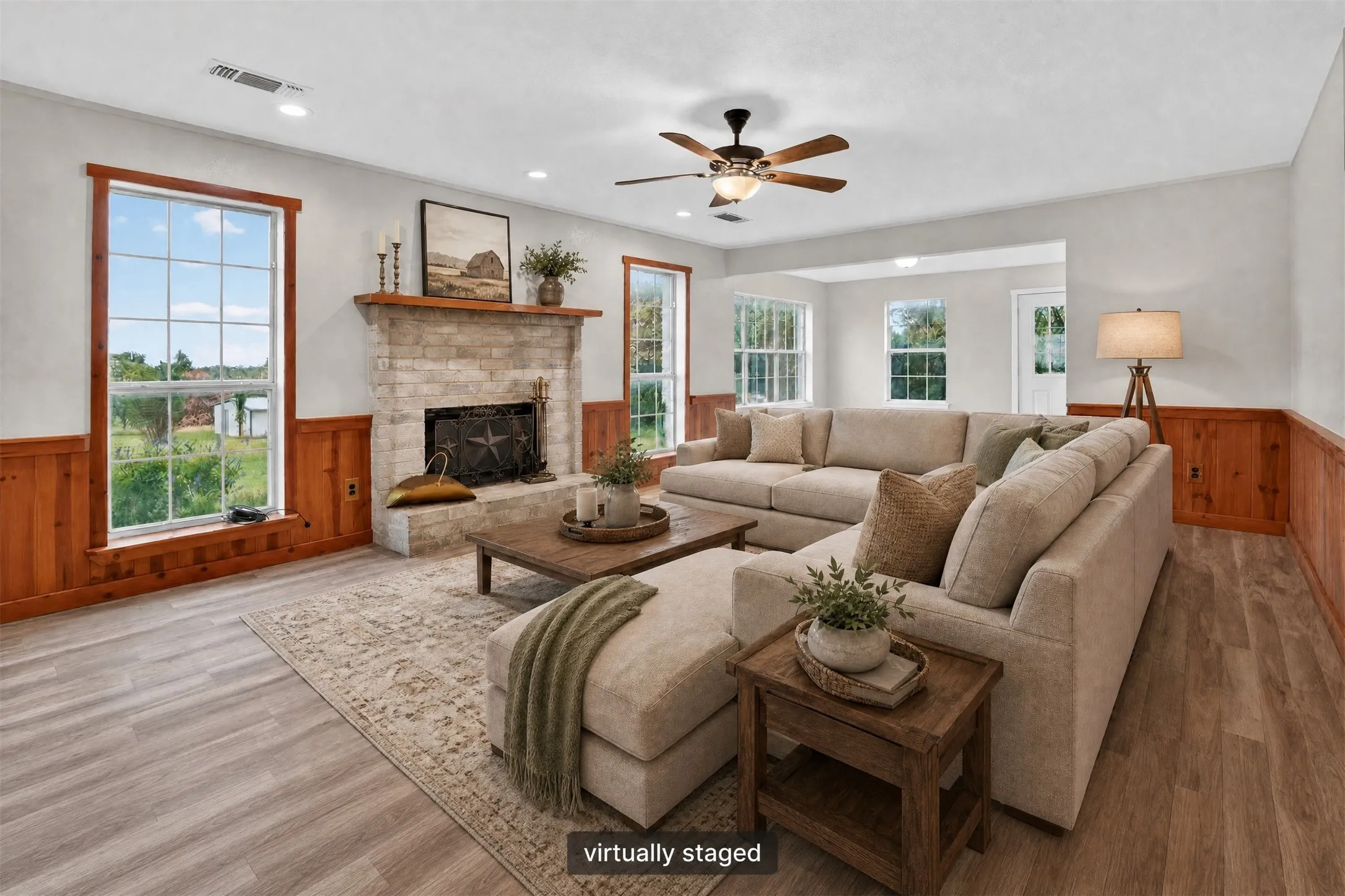 Stone fireplace with a wood mantle, wood-finish flooring, wood wainscoting, and recessed lighting