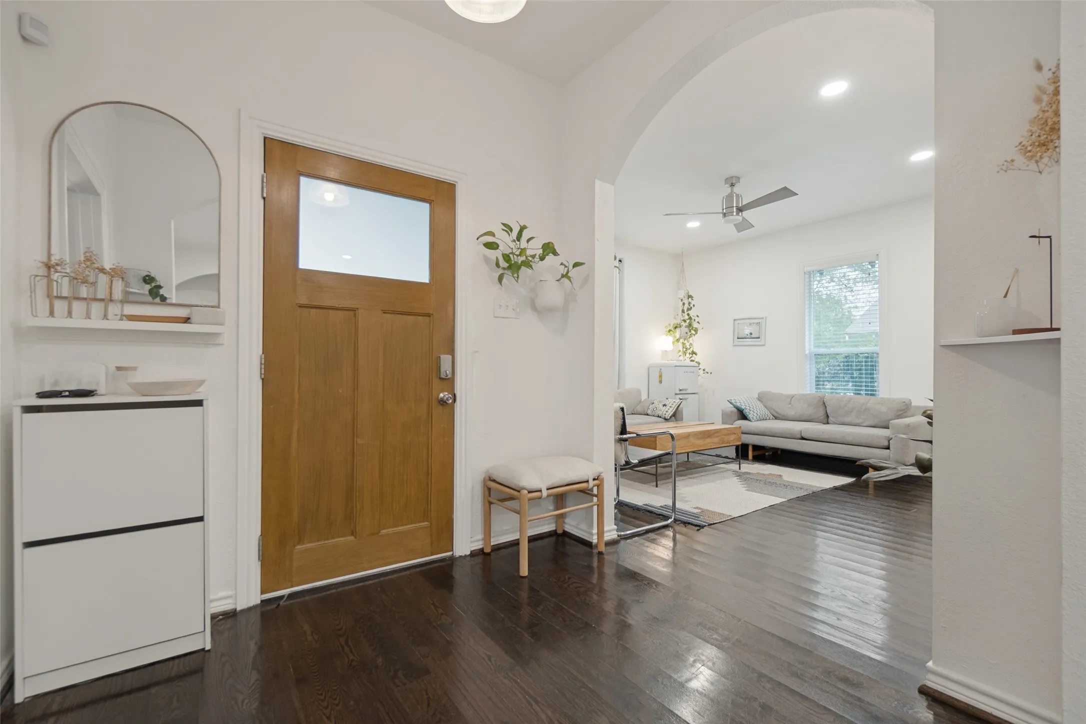 Welcoming foyer with dark wood-finish flooring, arched architectural detailing, and solid wood entry door with transom window
