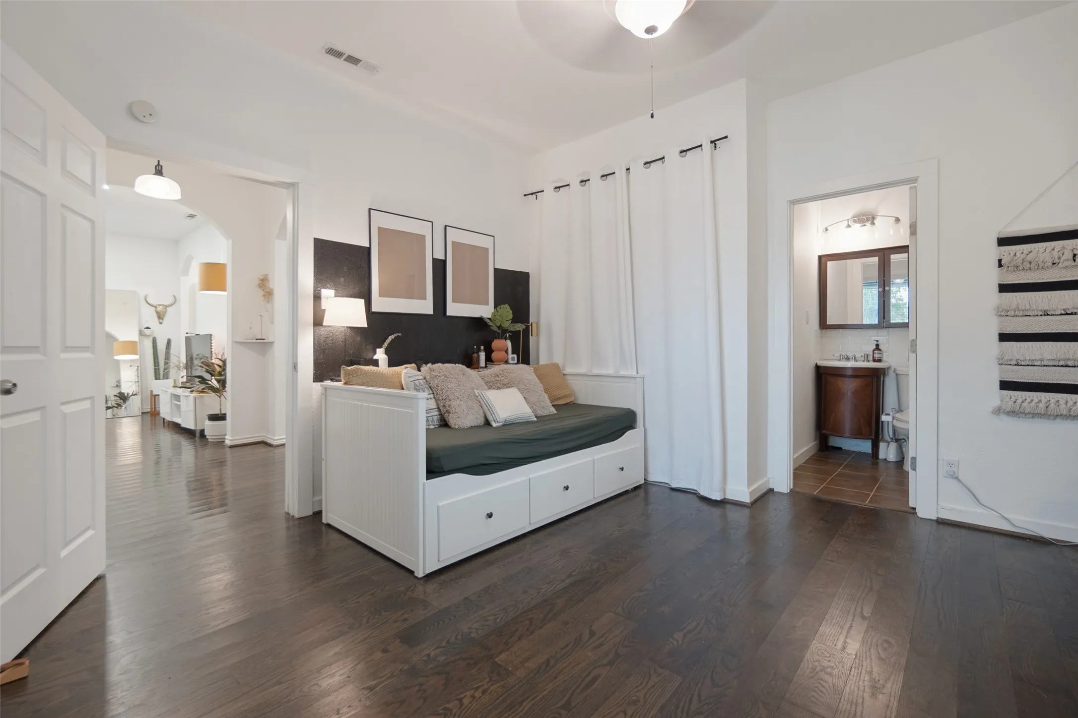 Dark wood-finish flooring throughout, white interior doors, and arched entryways