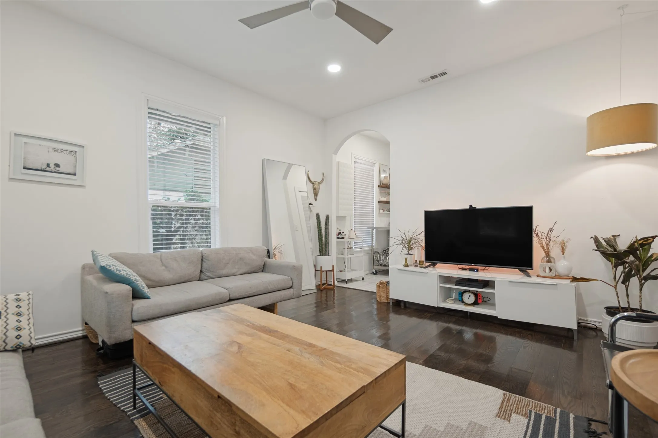 Recessed lighting, dark wood-finish flooring, high ceilings, ceiling fan, and arched entryway