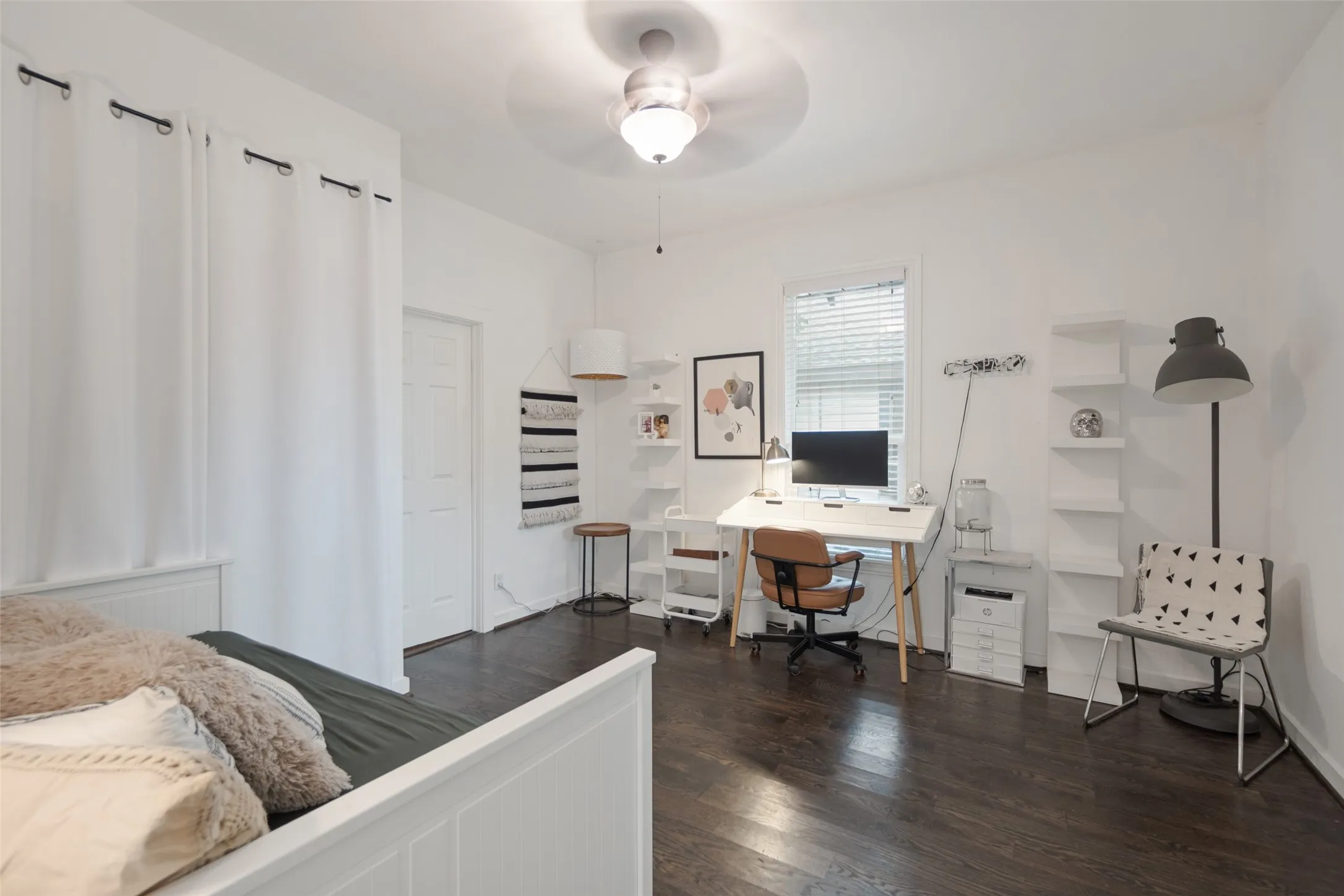 Dark wood-finish flooring with white walls and trim, featuring a ceiling fan with integrated lighting