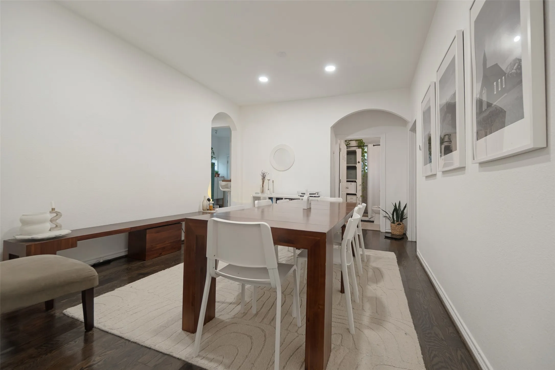 White walls, dark wood-finish flooring, recessed lighting, and arched doorways