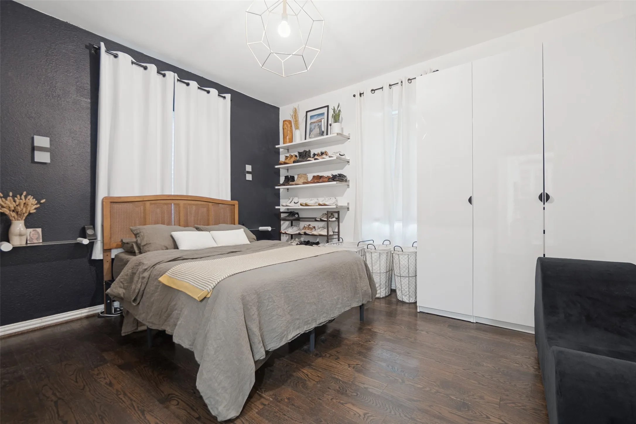 Dark wood-finish flooring, white built-in wardrobes, a geometric pendant light fixture, and floating wall shelves