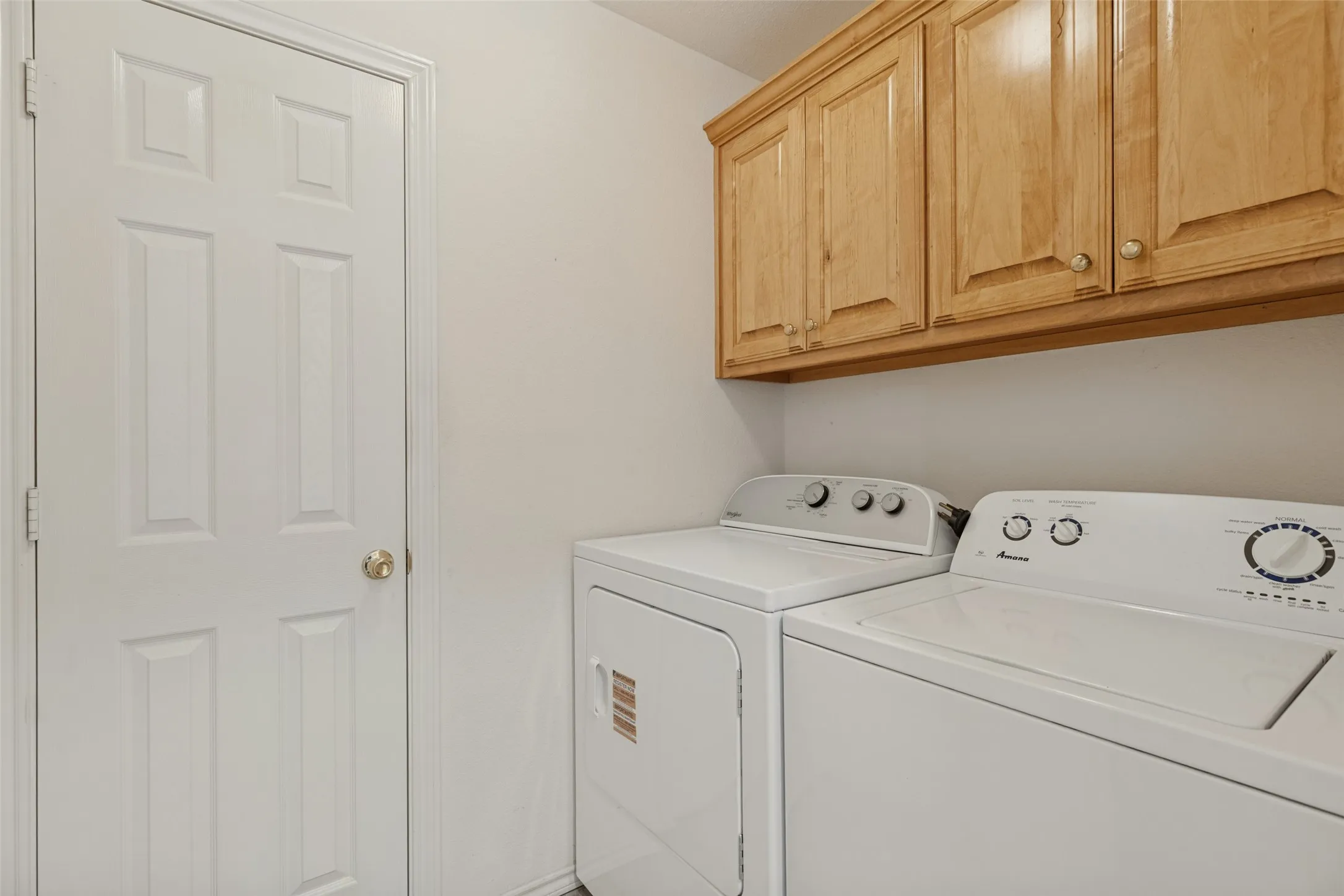 Laundry area featuring overhead wood cabinetry