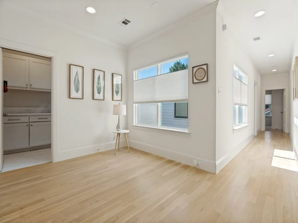 Bright interior space featuring light wood-finish flooring, recessed lighting, and large windows with cellular shades