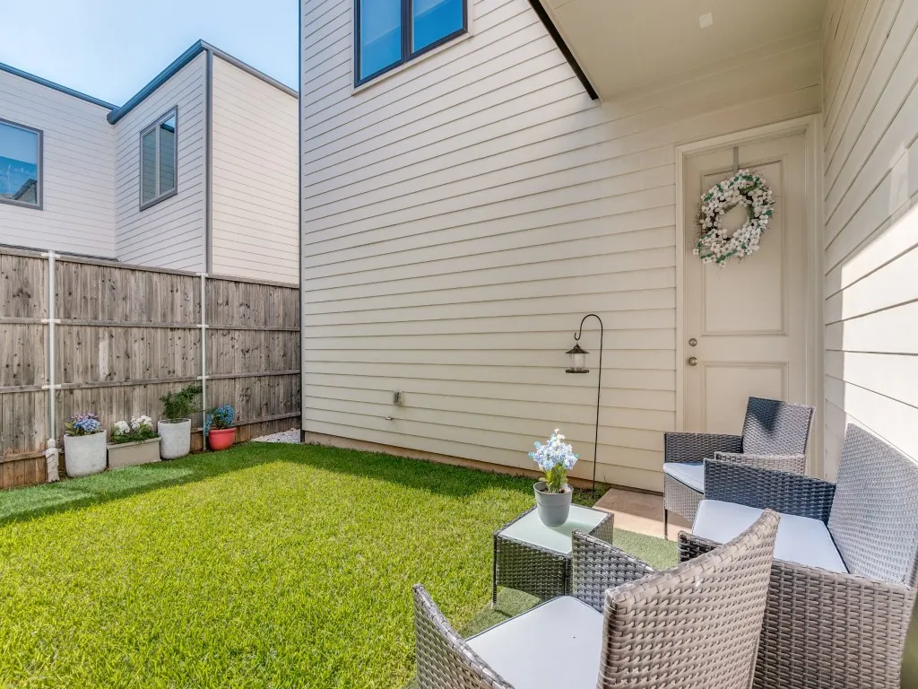 Private fenced backyard with lush green lawn, wood privacy fencing, and a paved patio area