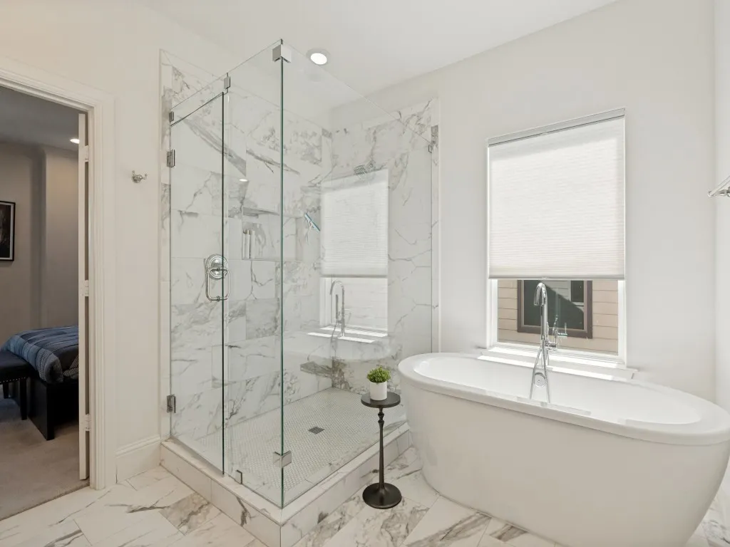 Luxurious bathroom featuring a spacious walk-in shower with frameless glass enclosure and marble-look tile surround