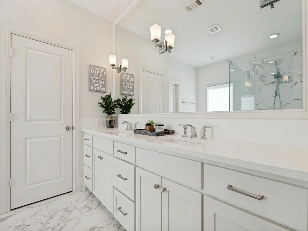 Dual vanity with white cabinetry and brushed nickel hardware, expansive white countertop, and large wall-mounted mirror