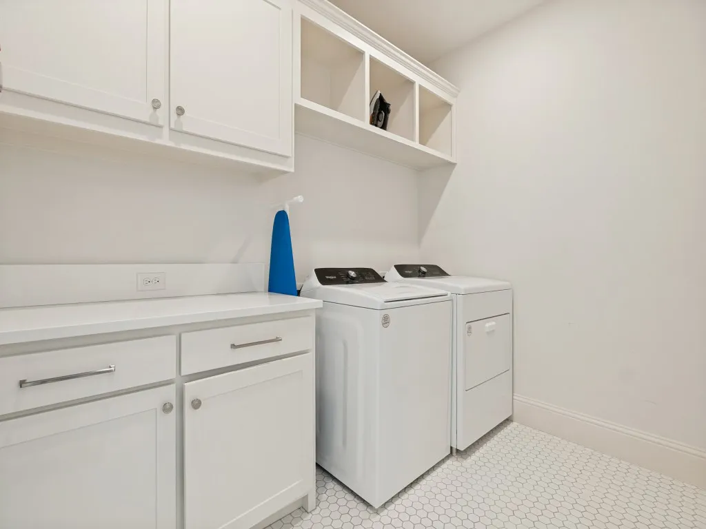 Dedicated utility space featuring white cabinetry with brushed nickel hardware, open shelving, a white countertop, and hexagonal floor tiling