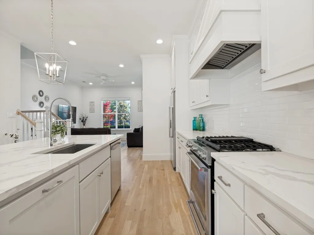 Modern kitchen featuring light wood-finish flooring, white cabinetry, and a subway tile backsplash