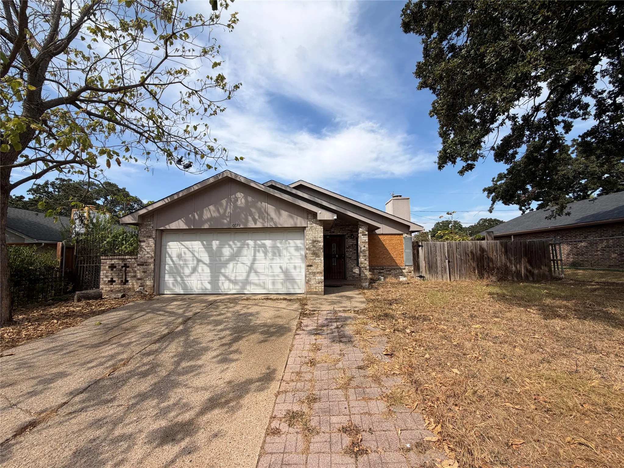 Single-story exterior with a two-car garage, brick and stone facade, and a paved walkway