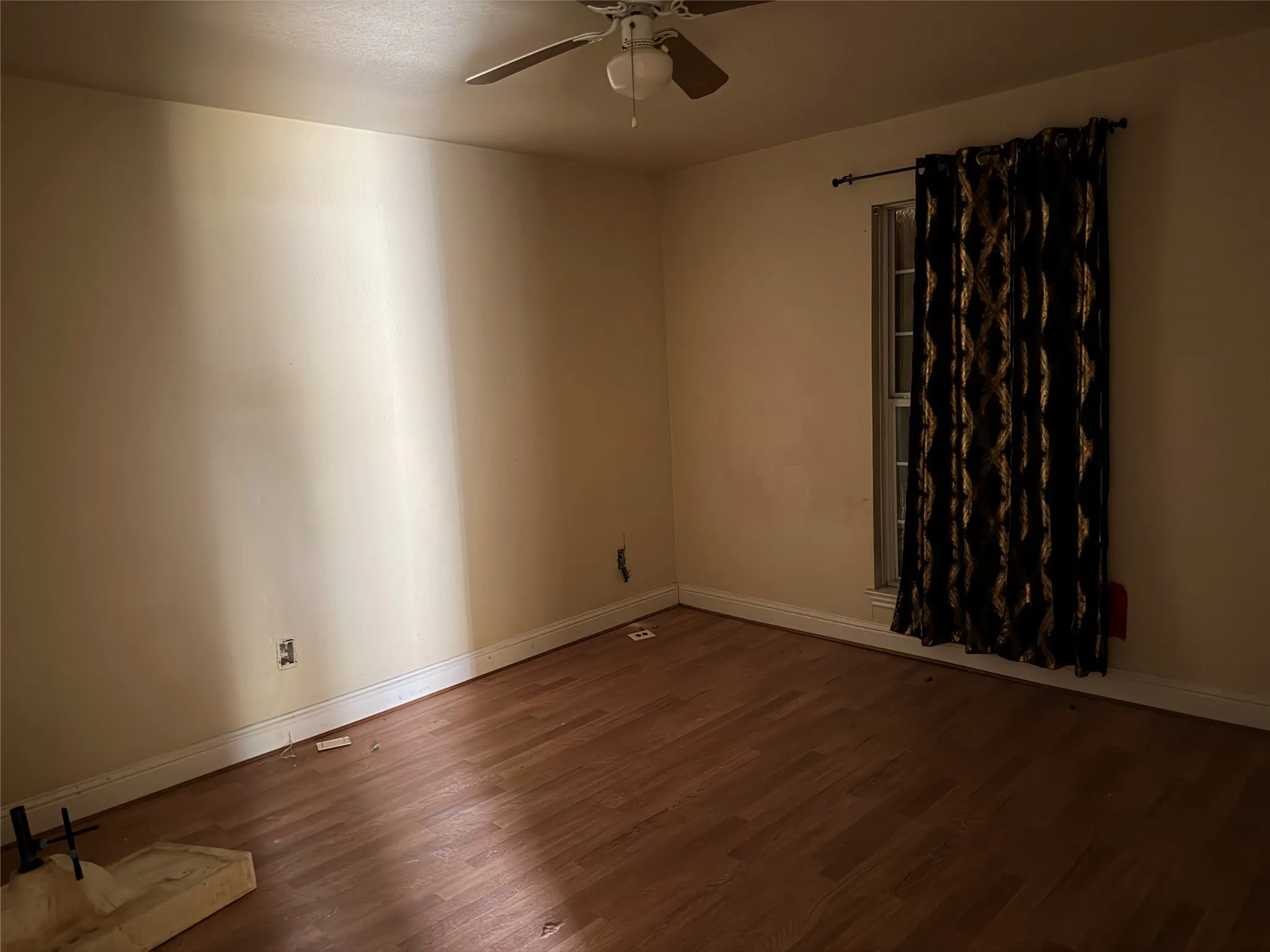 Wood-finish flooring with white trim and a single window