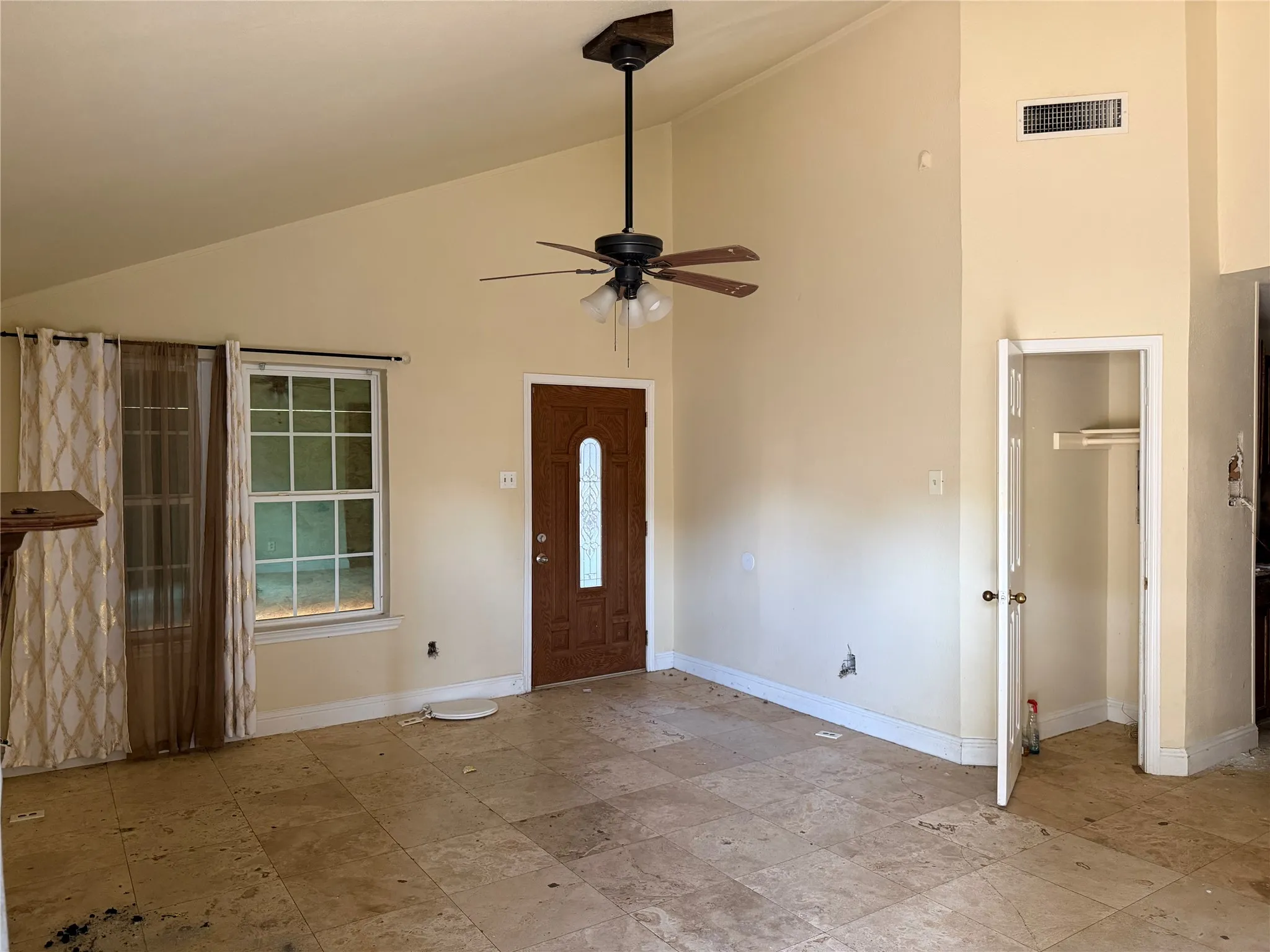 Vaulted ceiling with a ceiling fan, front entry door with decorative glass inserts, and square-tiled flooring