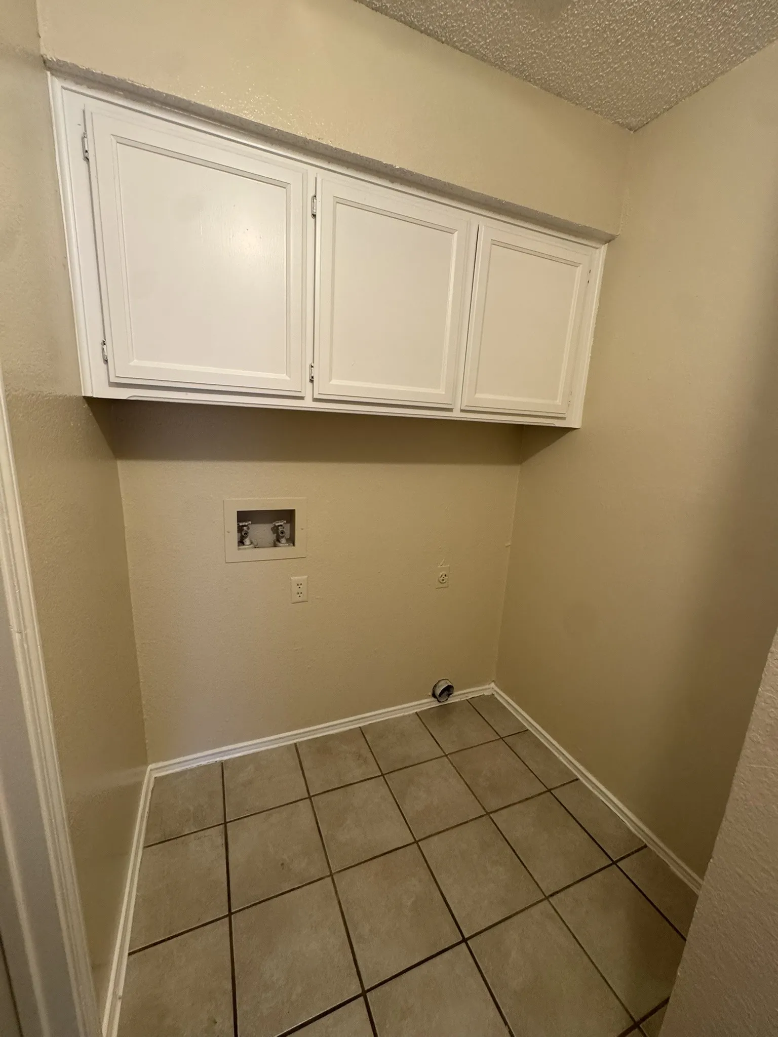 Utility space featuring overhead cabinetry, tile flooring, and appliance hookups