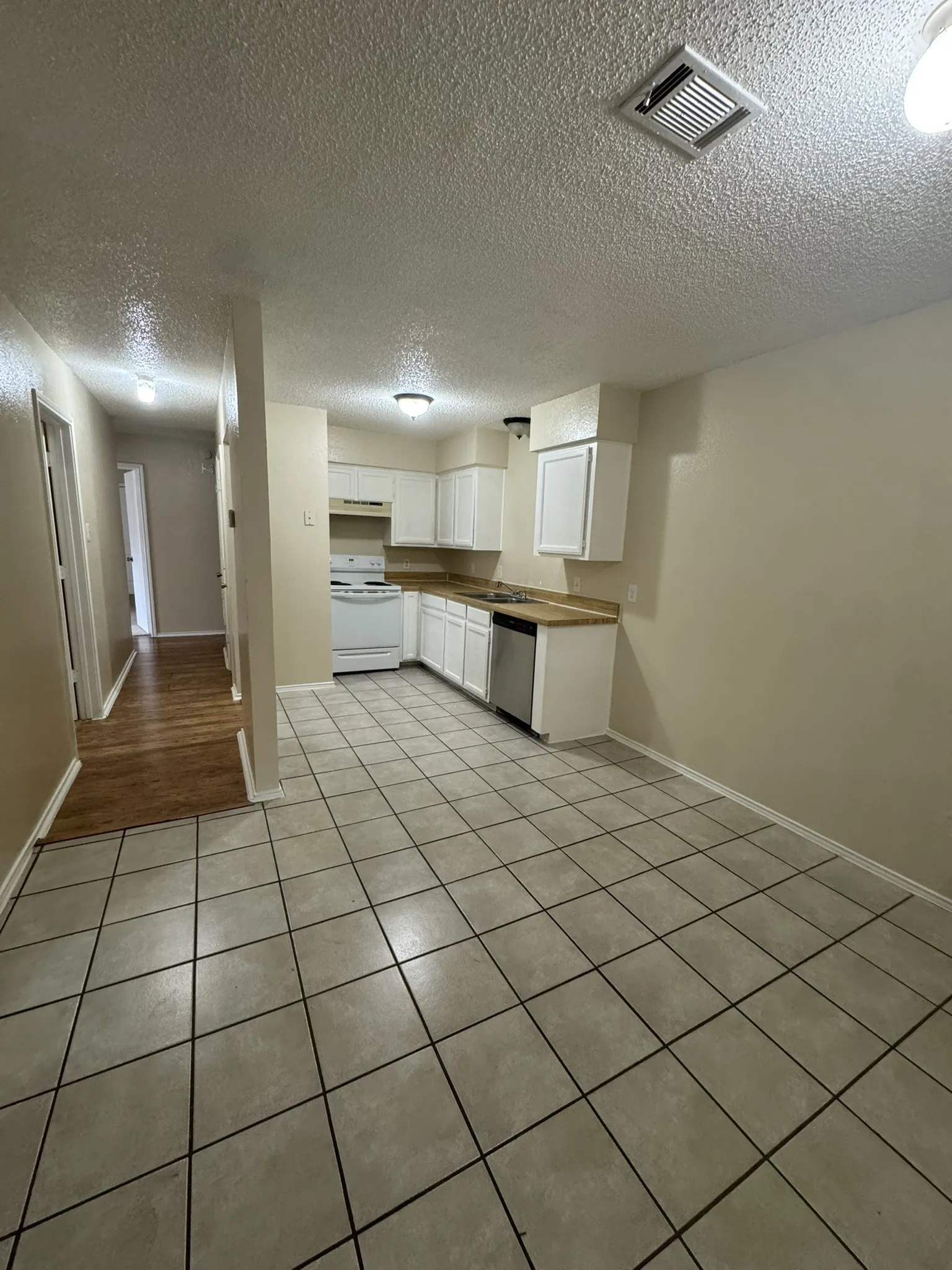 Kitchen featuring white cabinetry, wood-finish countertops, and a white appliance package