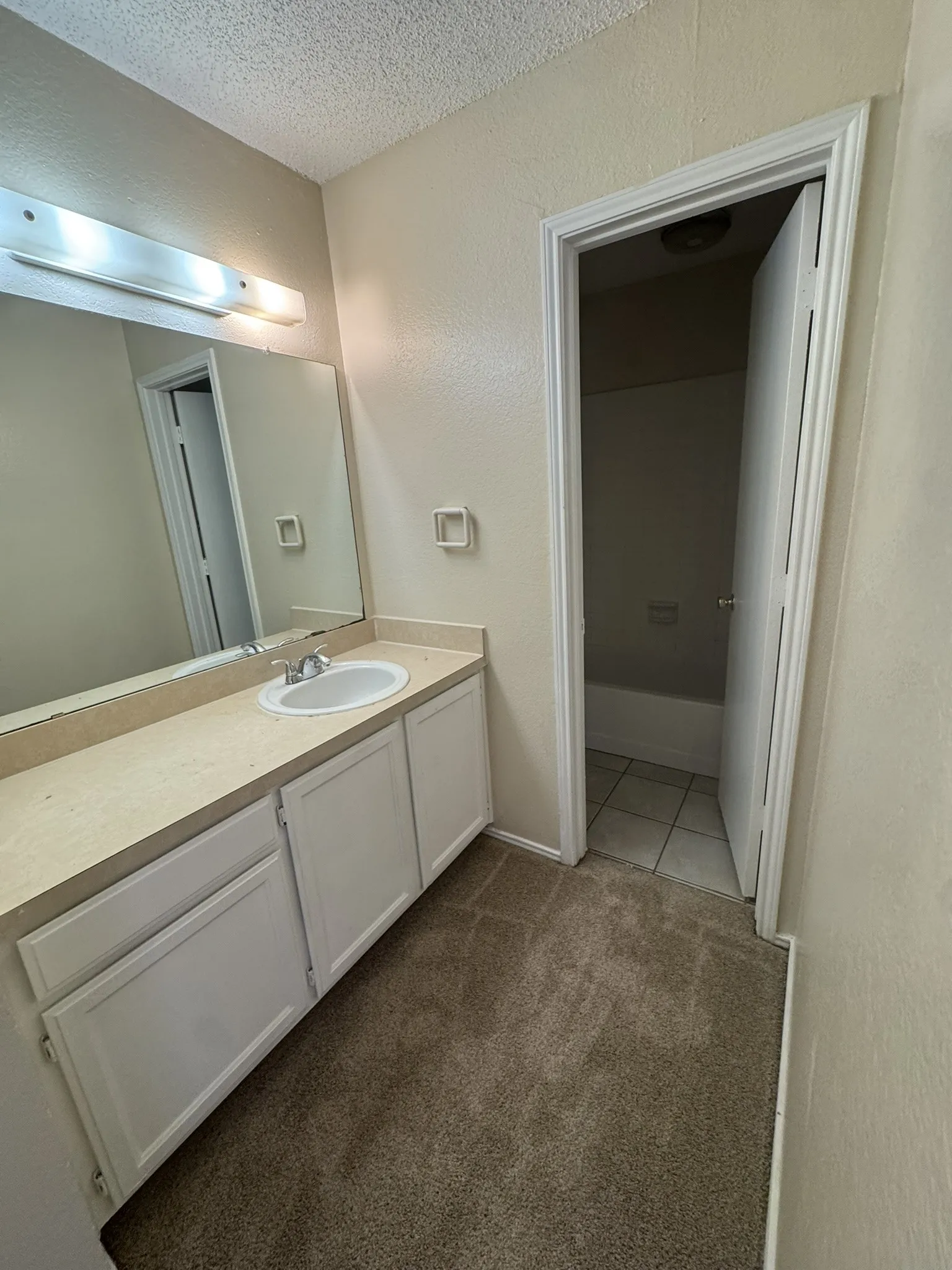 Bathroom featuring a vanity with an integrated sink, white cabinetry, and a full-width mirror