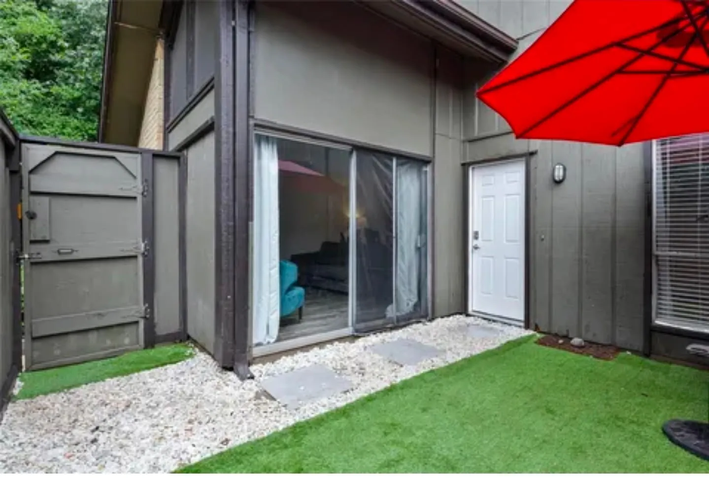 Enclosed patio featuring artificial turf, gravel pathways, and stepping stones